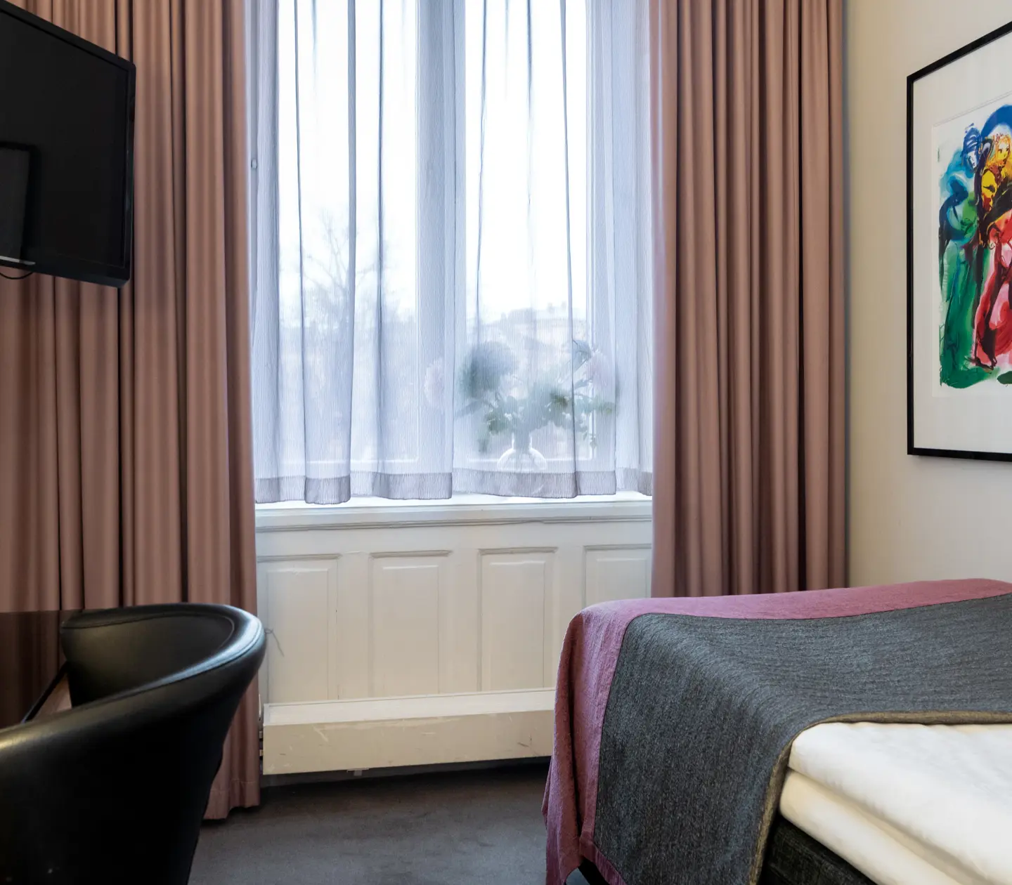 Hotel room with single bed, desk, TV, blackboard and large window