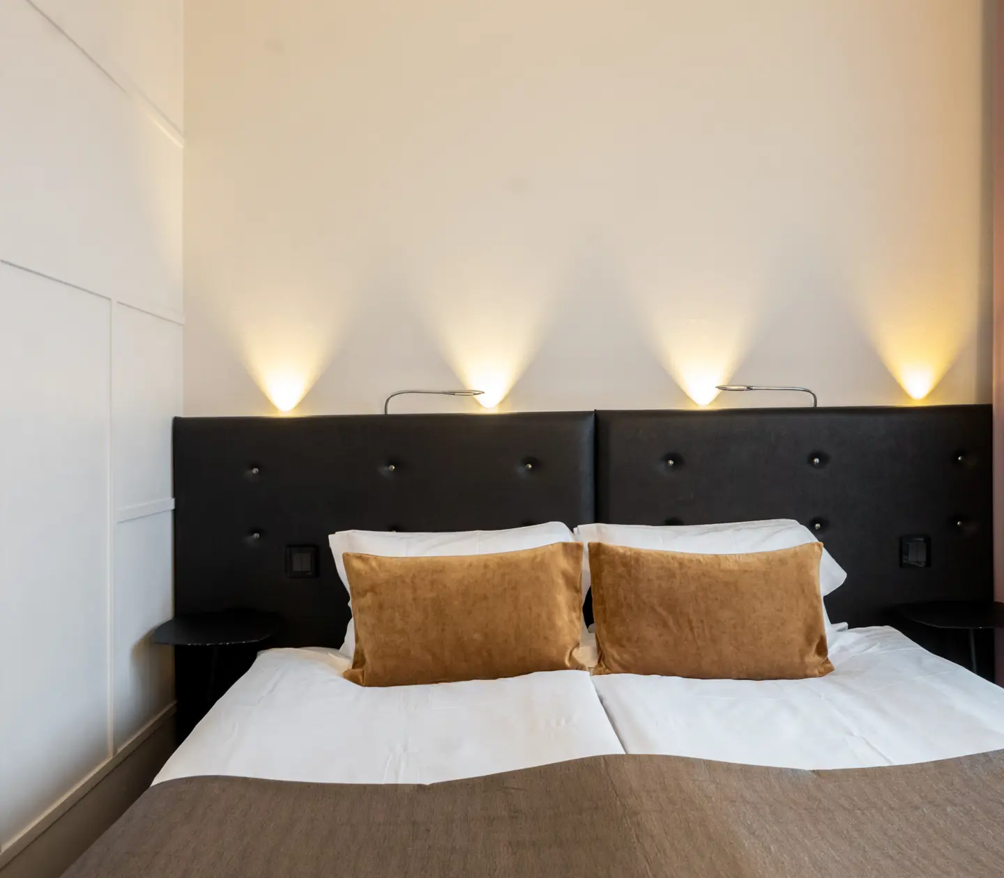 Hotel room with window, double bed with black headboard, lamps and yellow pillows