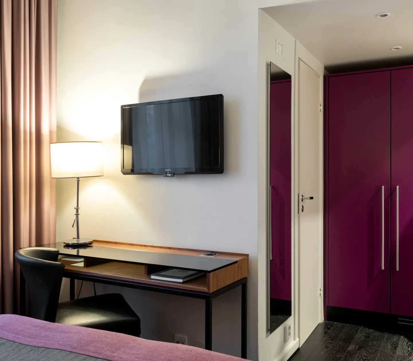 Hotel room with desk, TV, mirror and wardrobe