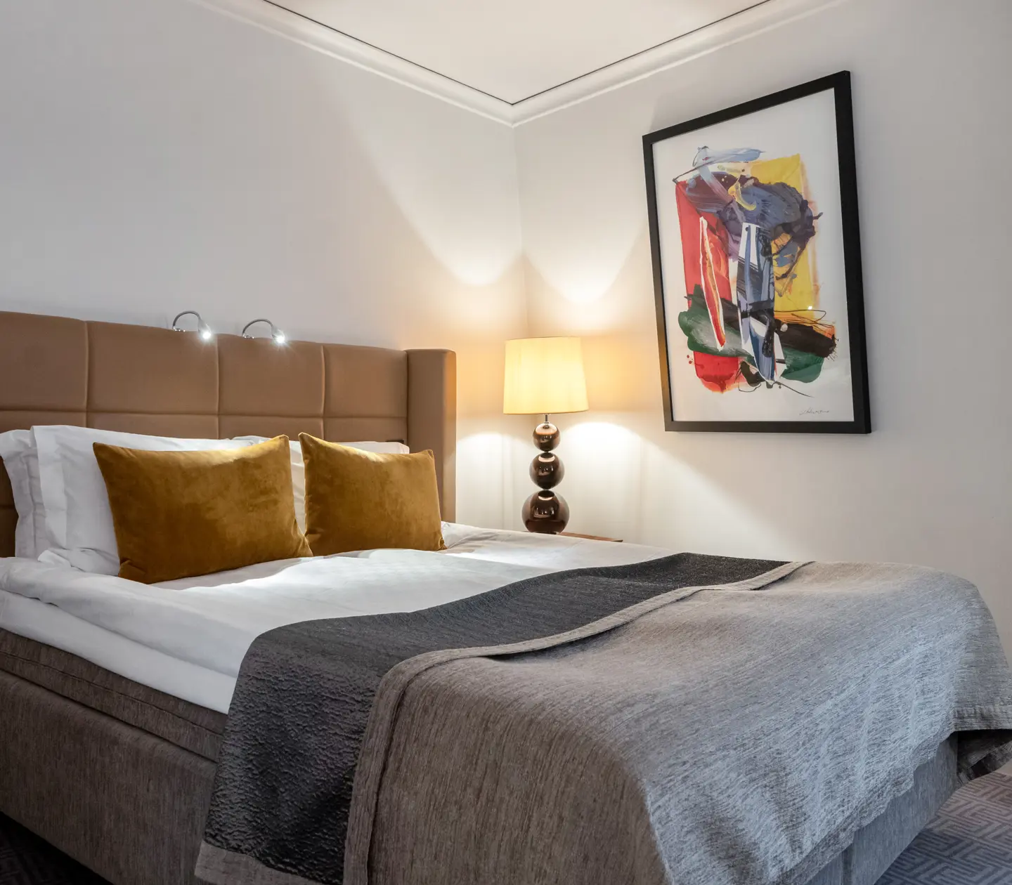Cozy hotel room with double bed with yellow headboard, lamps and blackboard