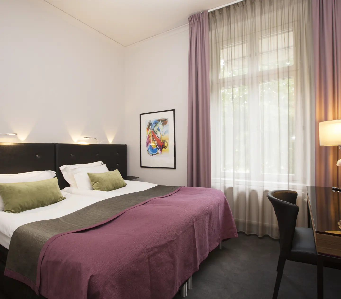 Bright hotel room with double bed, desk, blackboard and large window