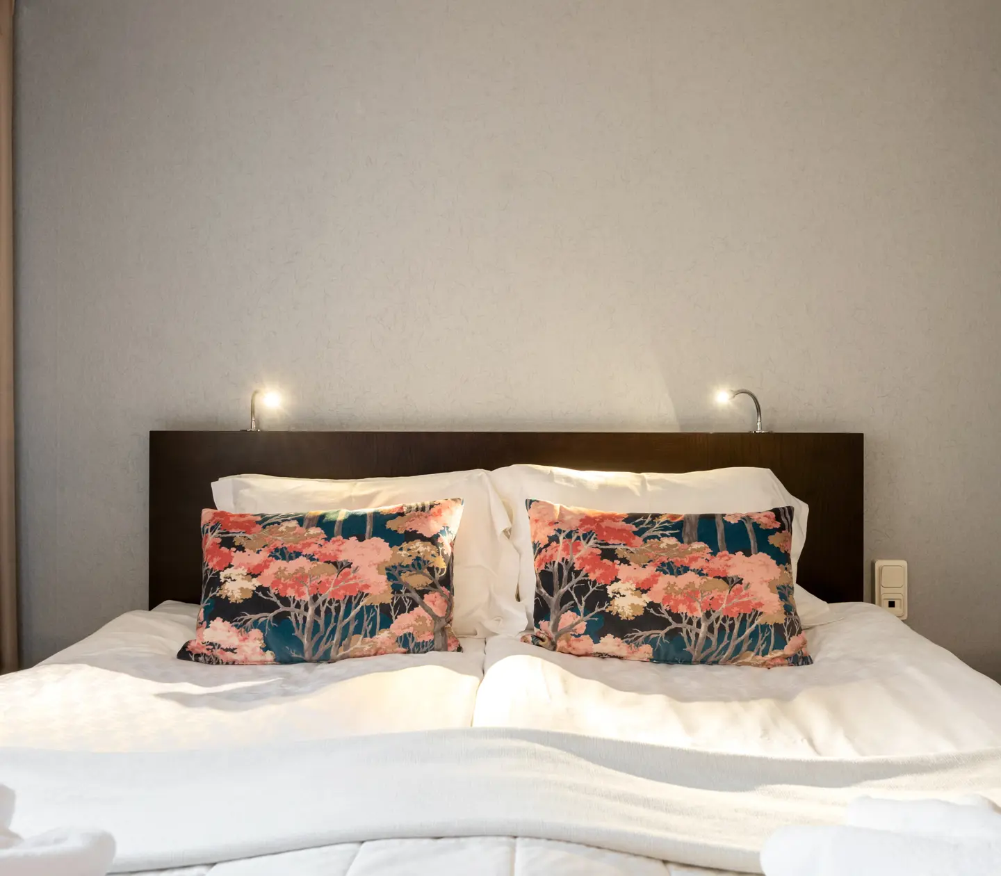 Hotel room with double bed with floral pillows and lamps