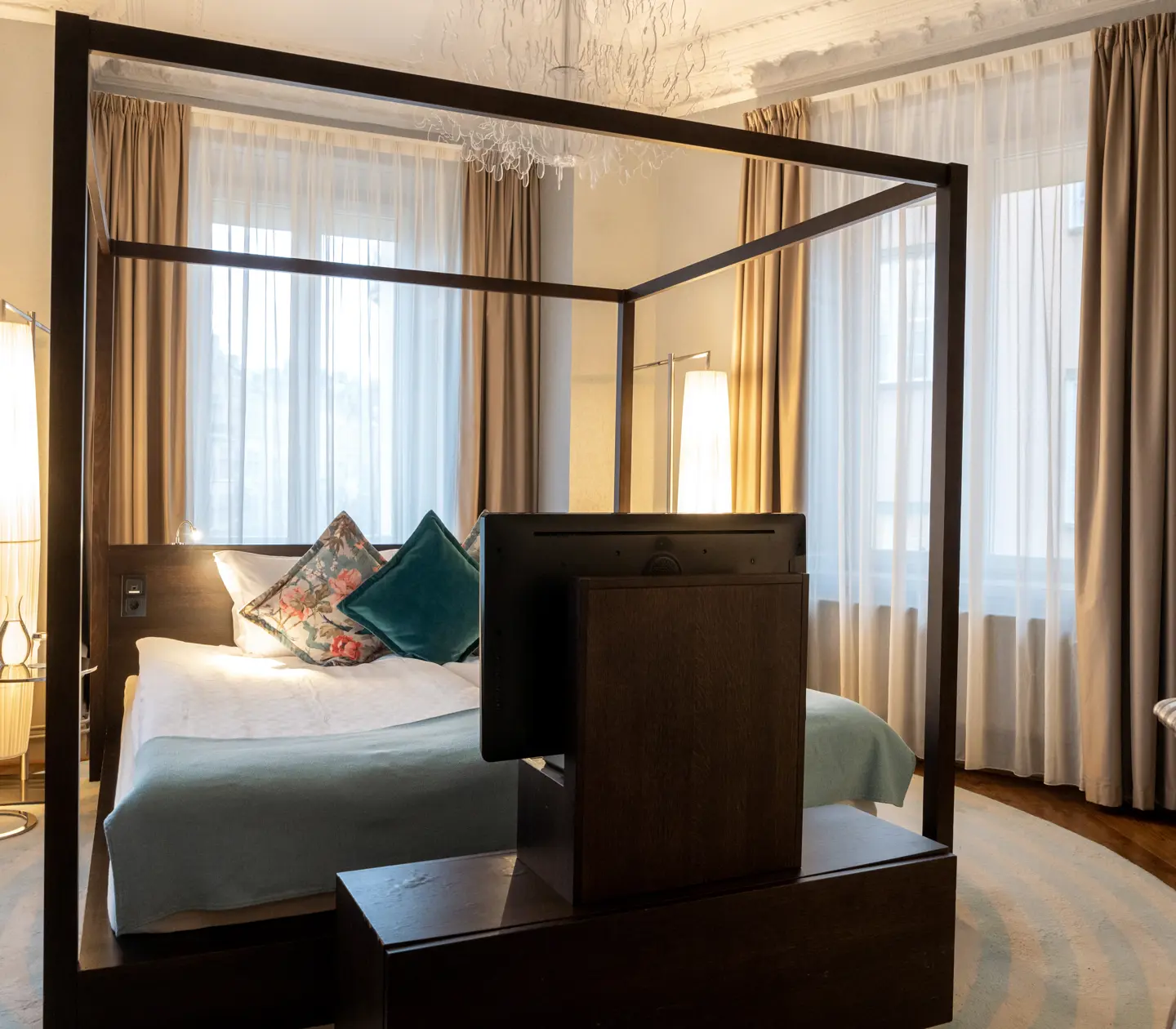 Luxurious hotel suite with large double bed, window, curtains and TV