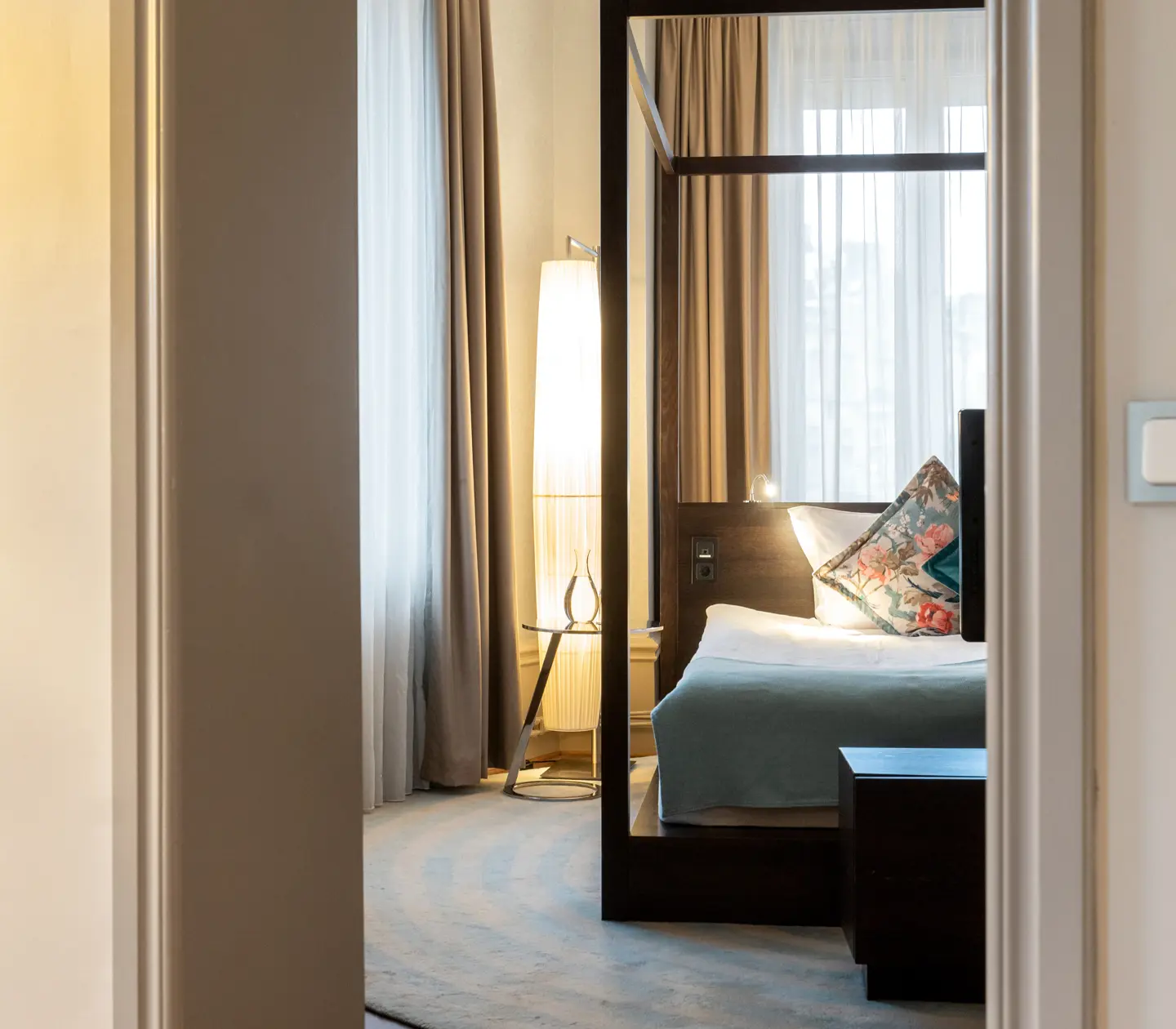 Cozy hotel suite with double bed, floor lamp and TV