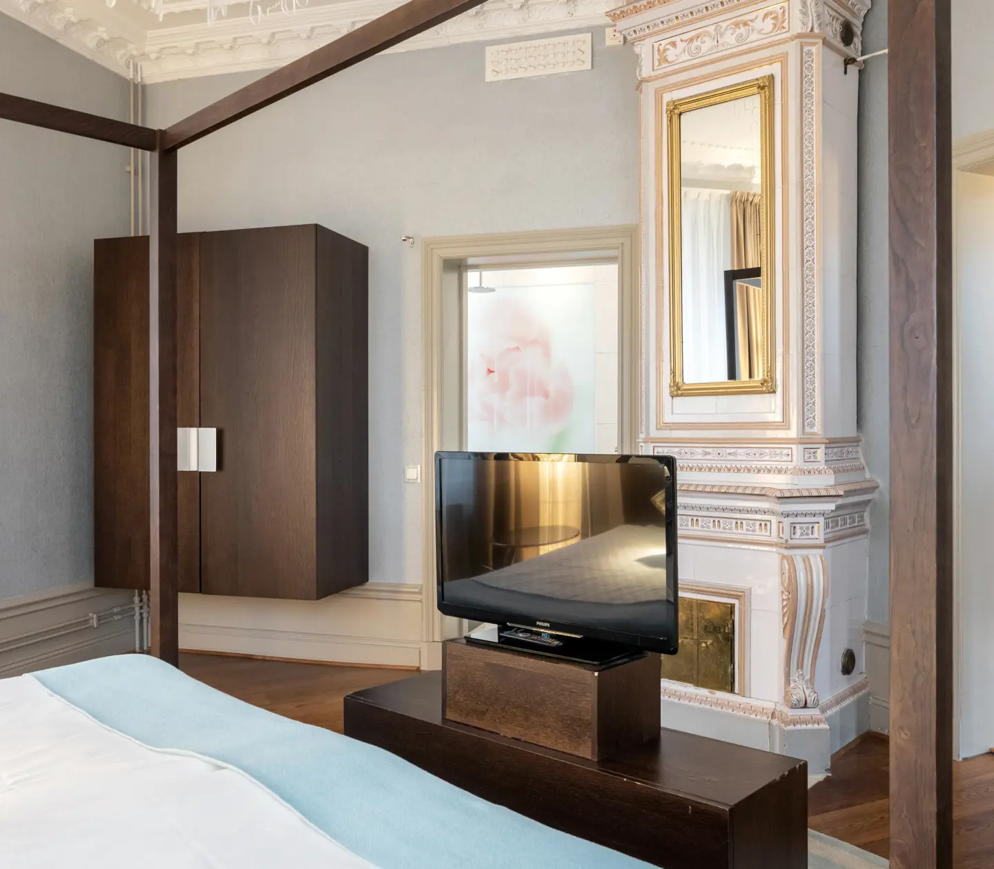 Luxurious hotel suite with double bed, tiled stove and TV