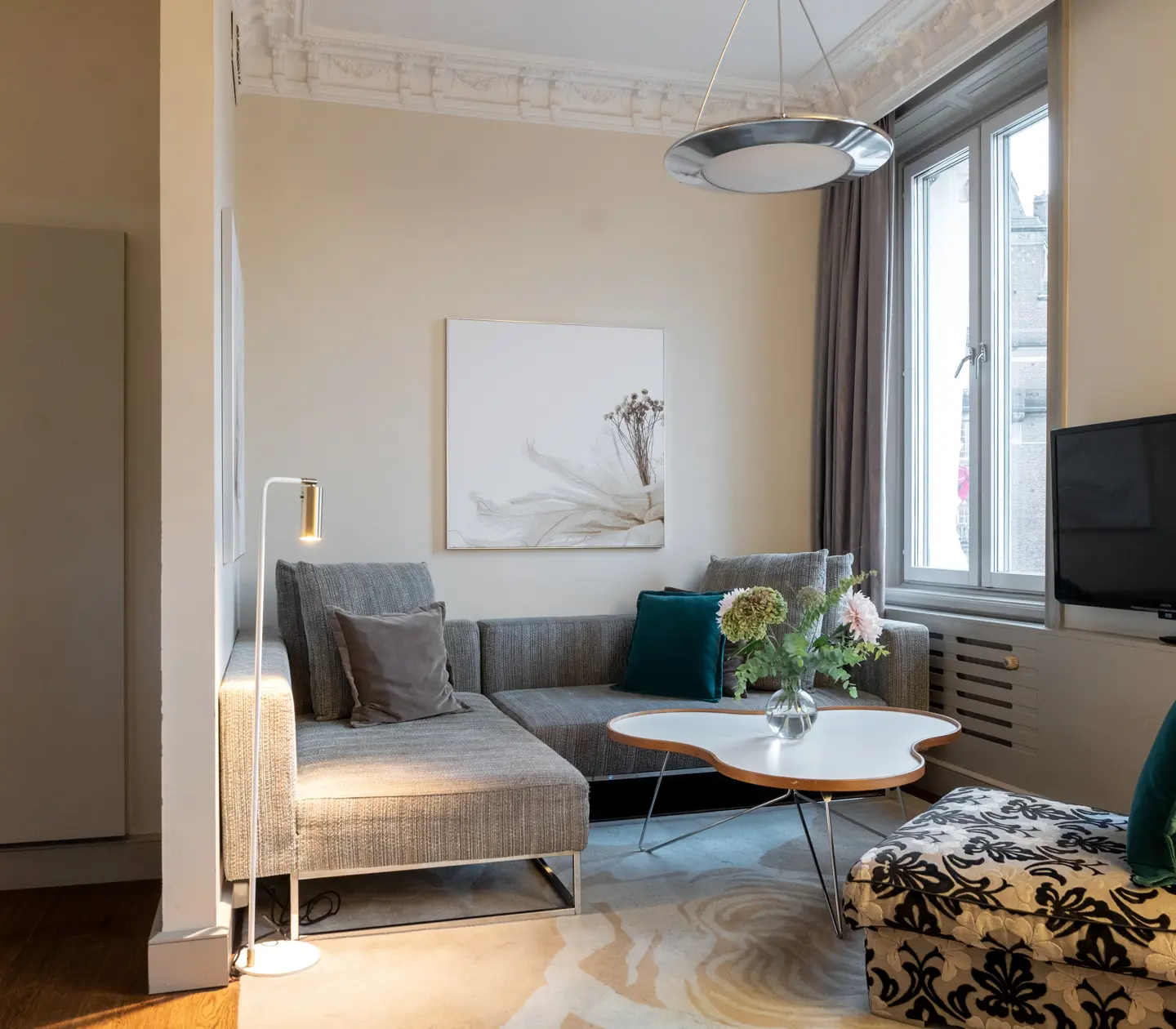 Bright hotel suite with wardrobes, sofa, TV and window