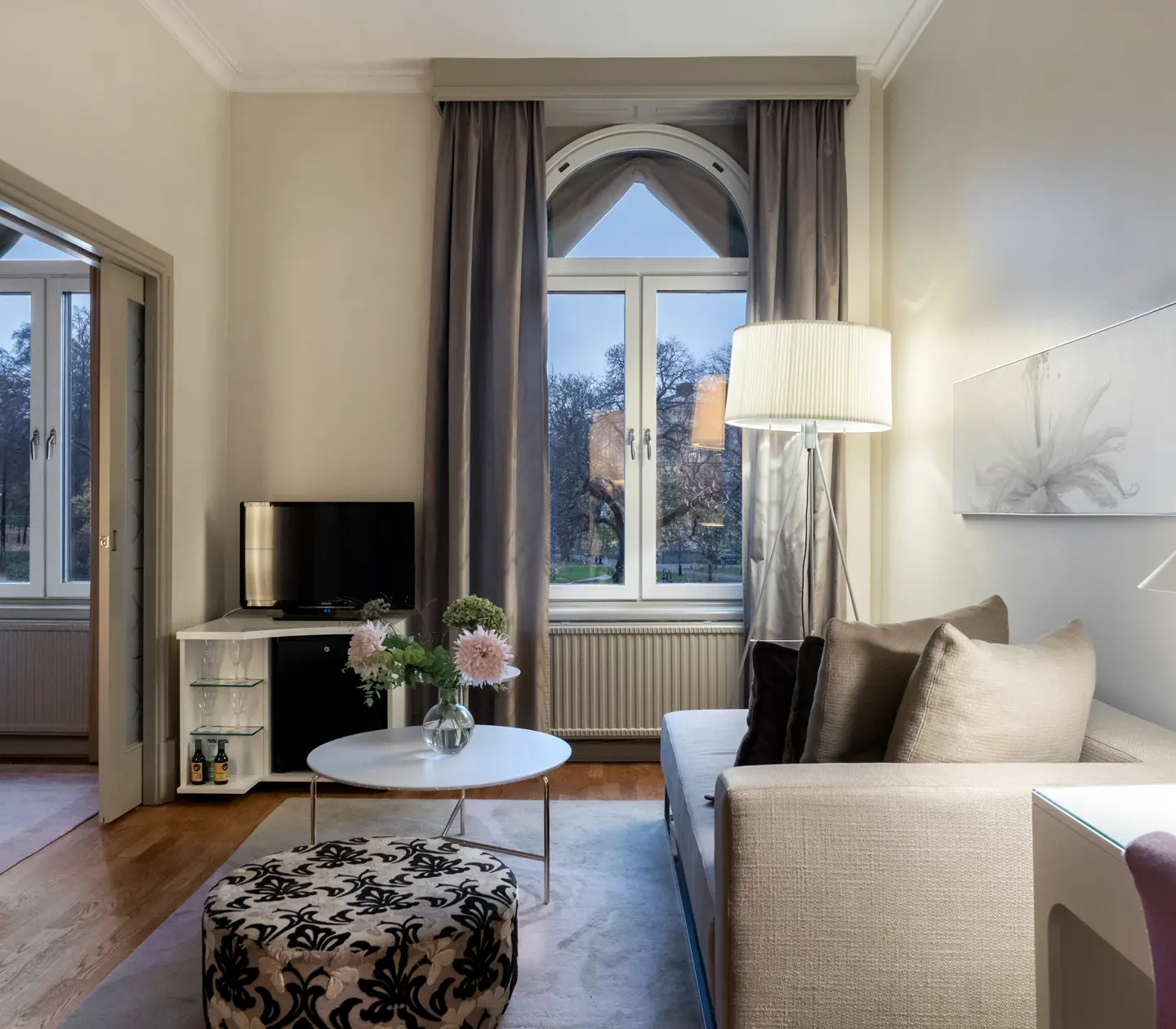 Bright hotel room with desk, sofa, TV and large window