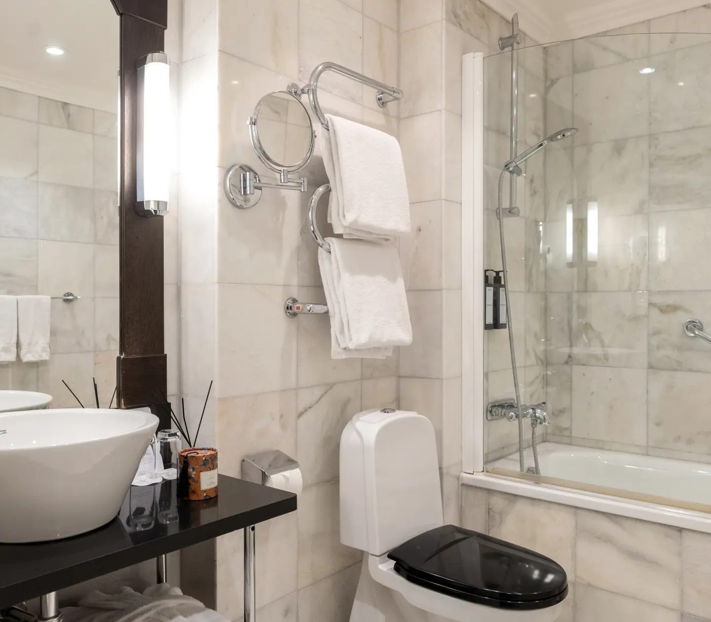 Bright bathroom with toilet, bathtub, heated towel rail, sink and mirror