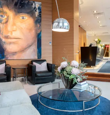 Hotel lobby with sofa, painting with face, bouquet and reception desk