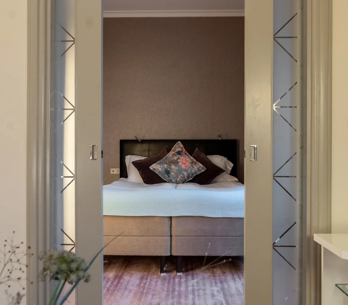 Cozy hotel suite with large double bed and doors into the bedroom