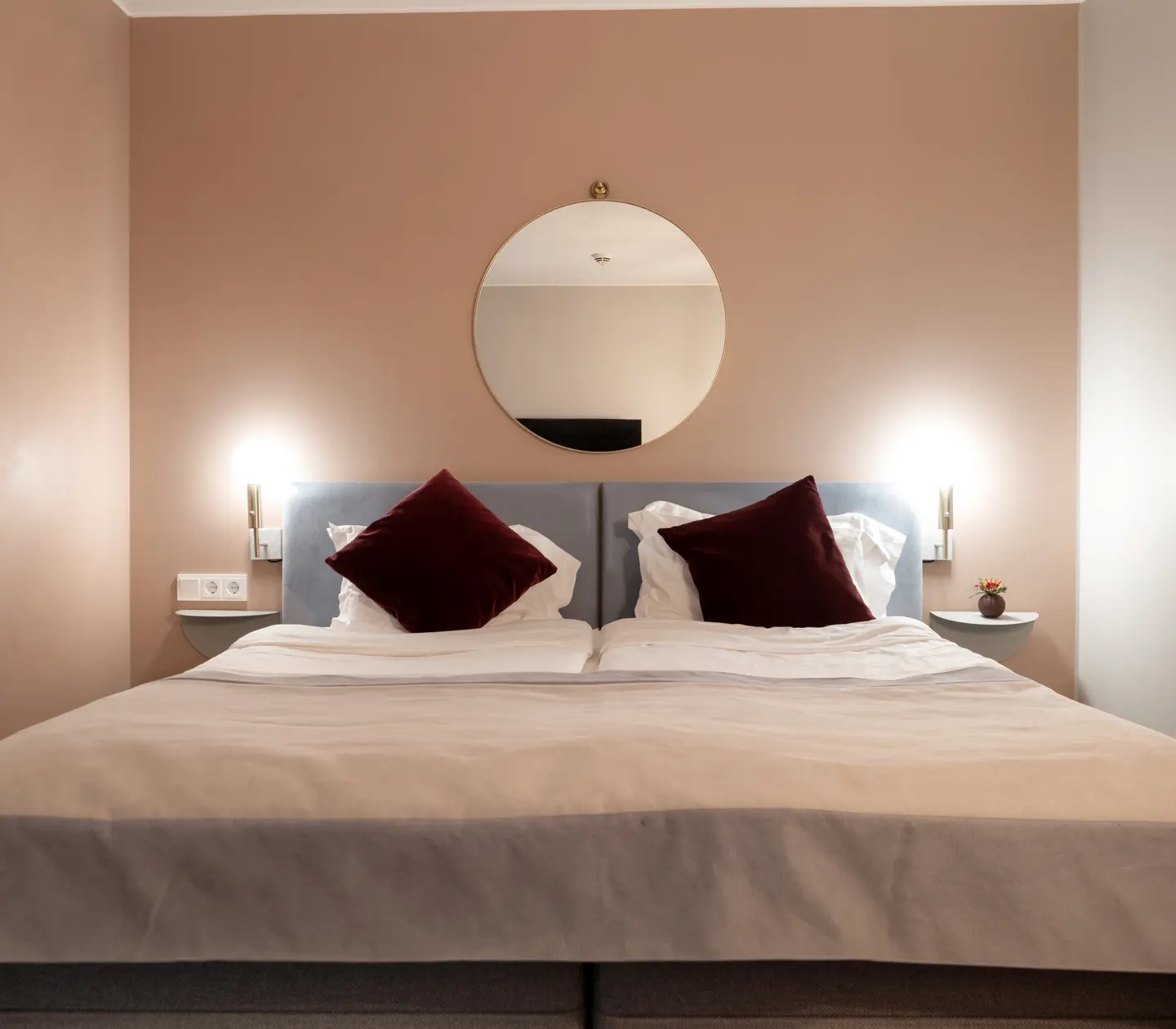 Double bed with round wall mirror over the headboard