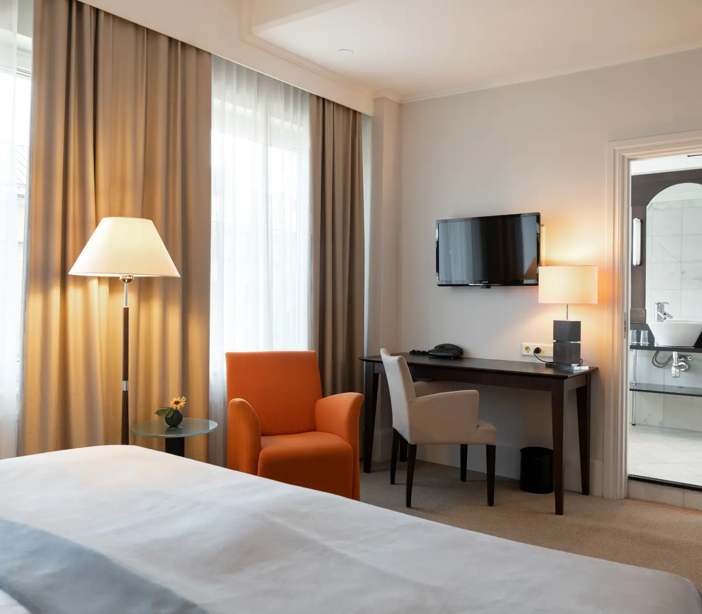 Desk, floor lamp, TV and entrance to bathroom in hotel rooms