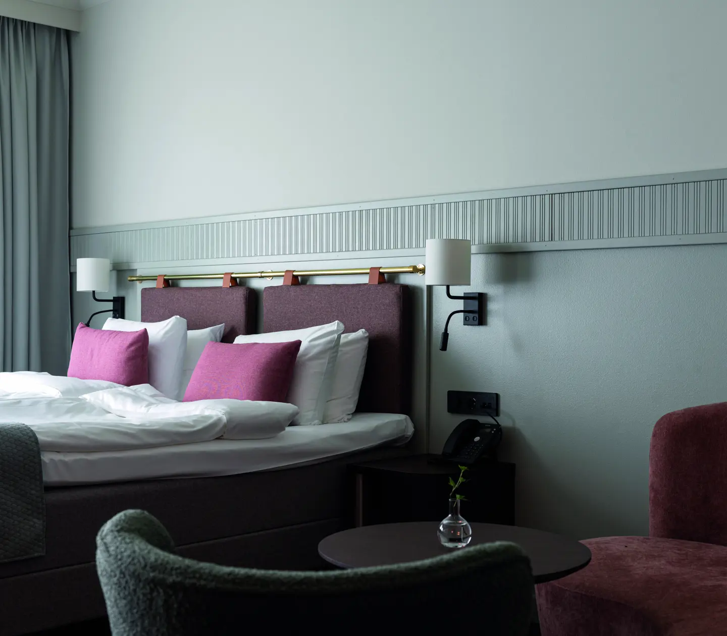 Double bed with pink pillows and a seating area