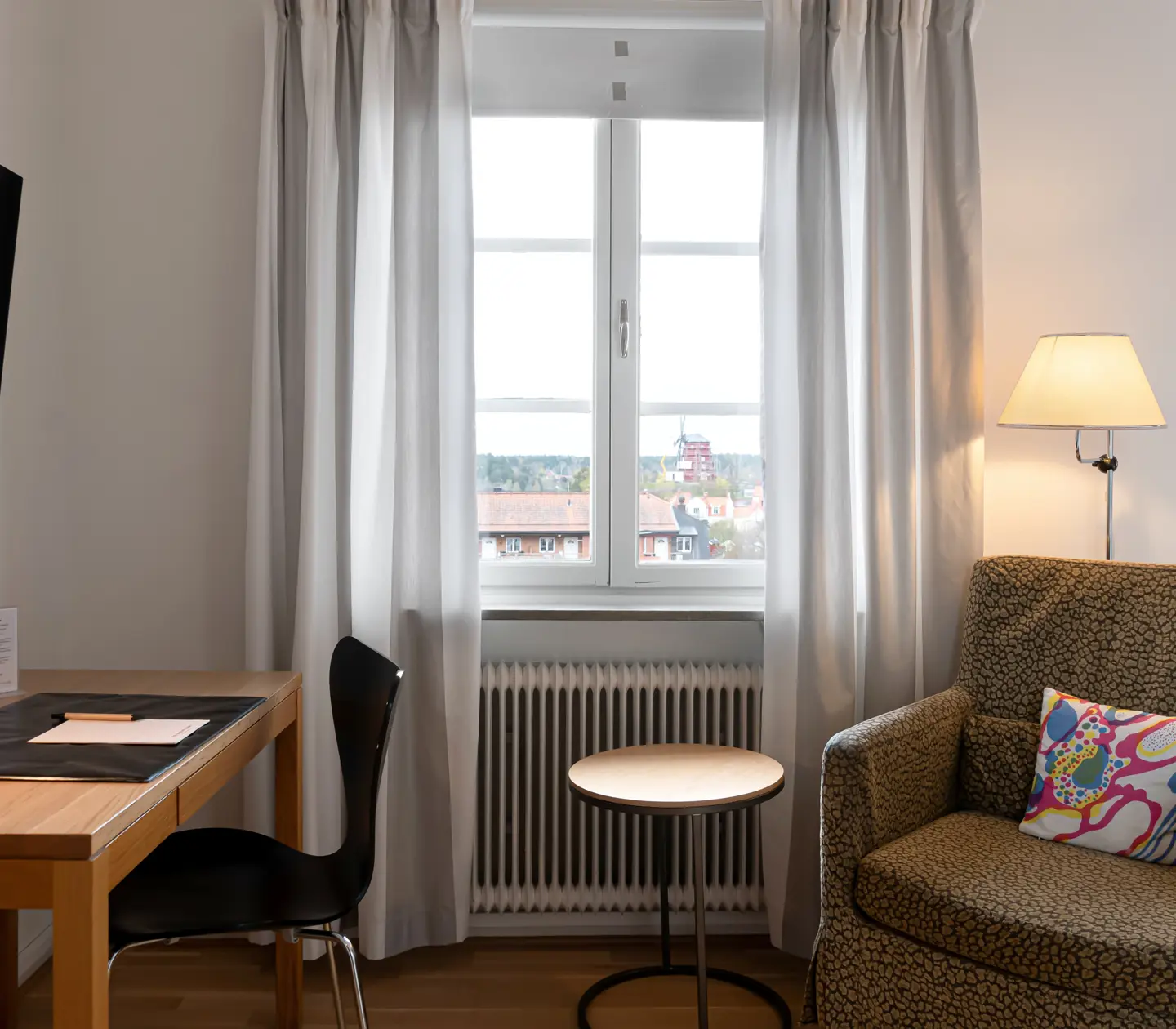 Bright hotel room with desk, armchair and window