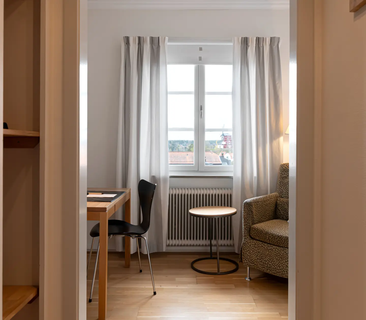Bright hotel room with desk, armchair and window