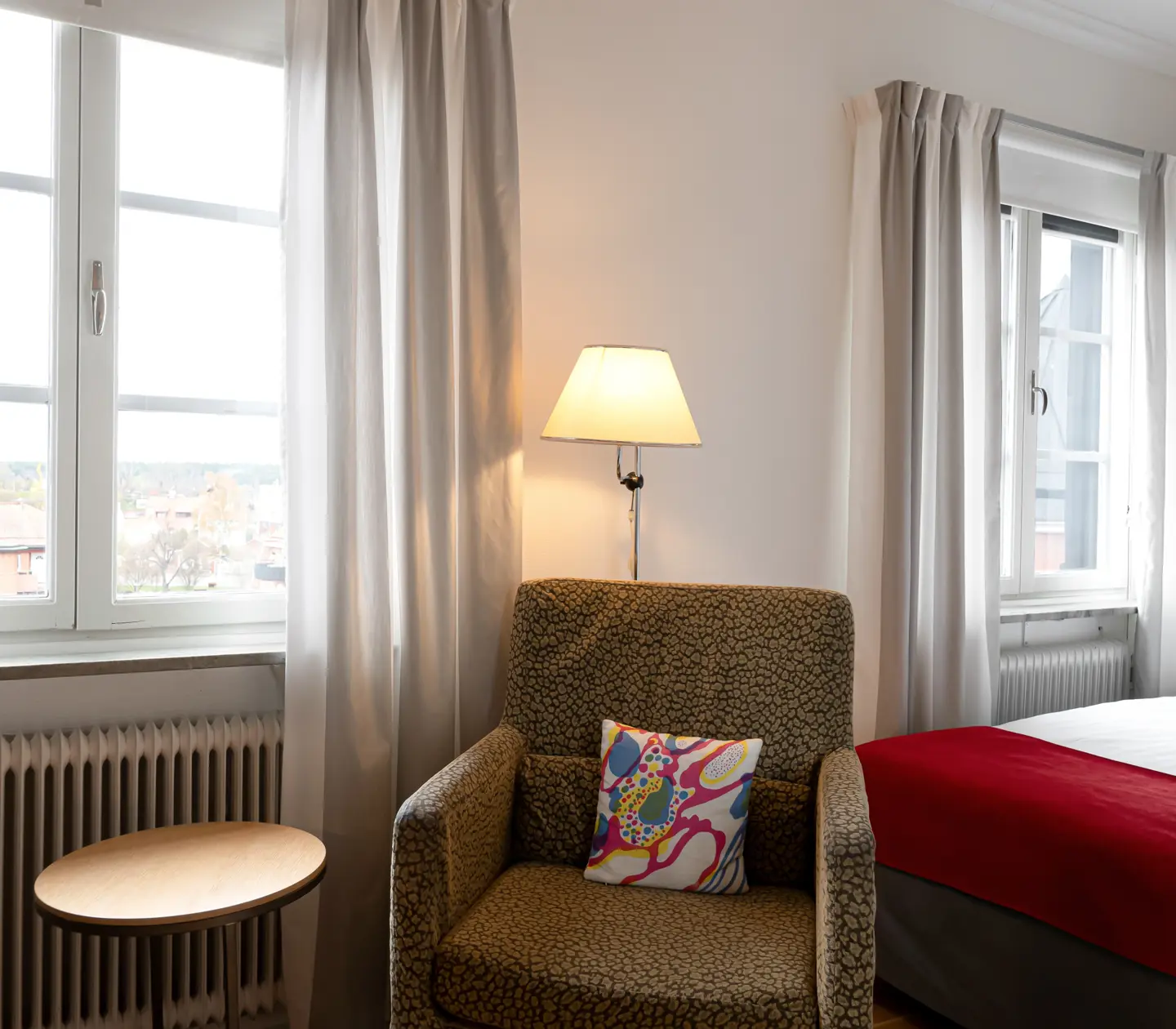 Bright hotel room with bed, armchair and window