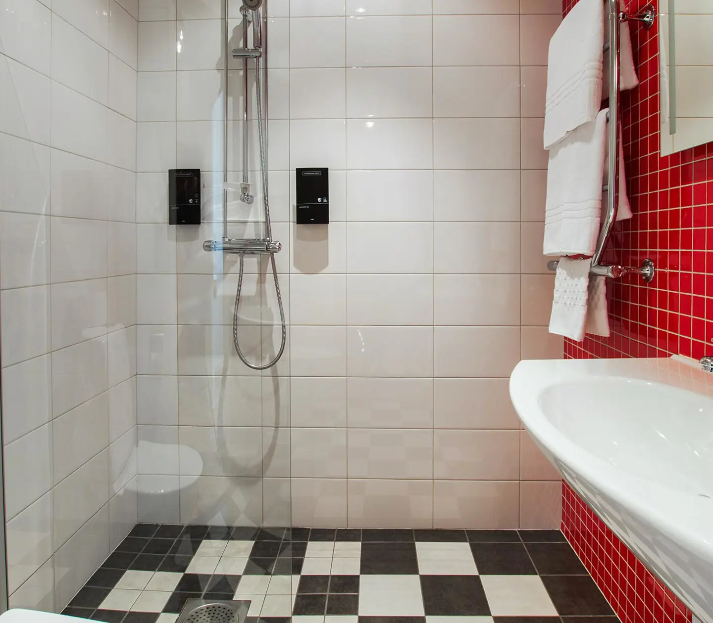 White and red bathroom with towels, sink and shower