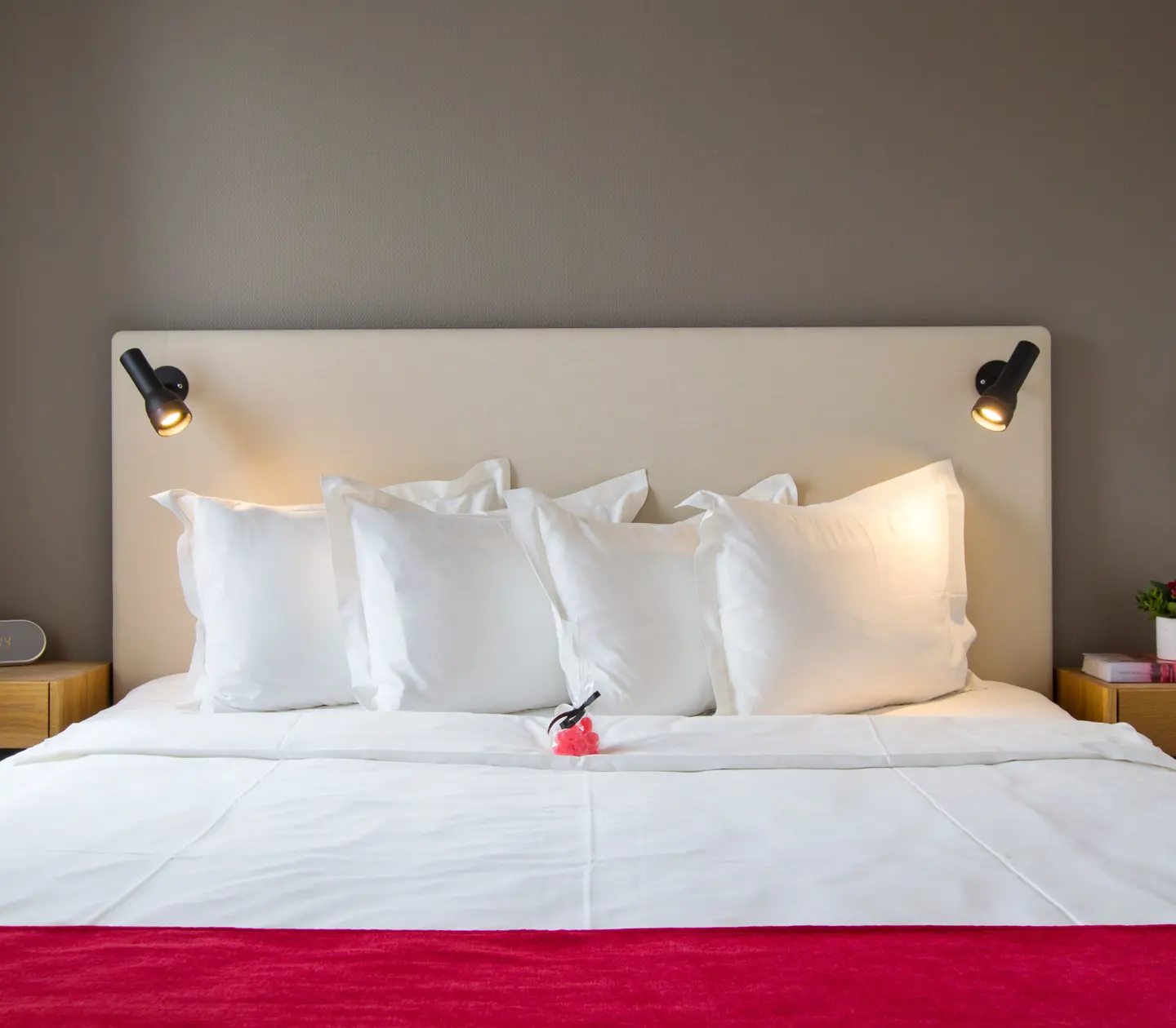 Cozy hotel room with bed, bedside lamps and small candy bag on the bed