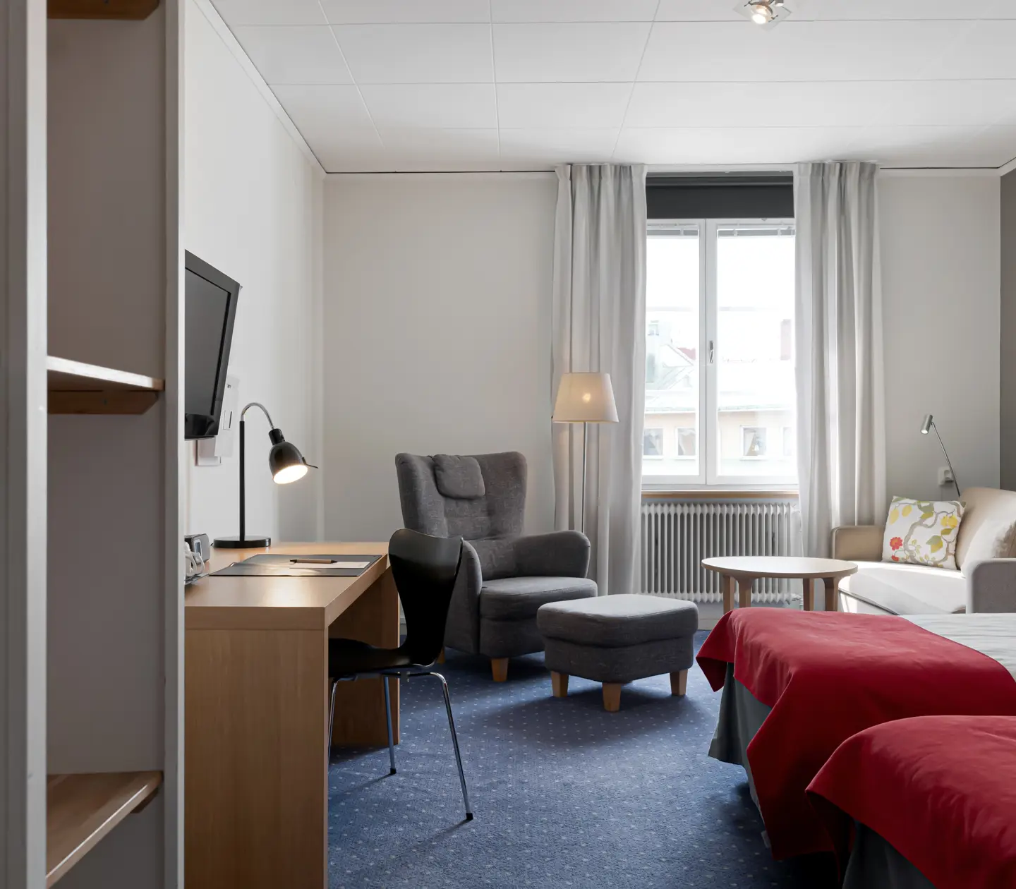Hotel room with bed, sofa group and desk
