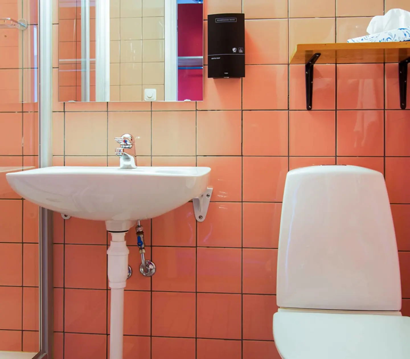 Orange bathroom with toilet, sink and mirror
