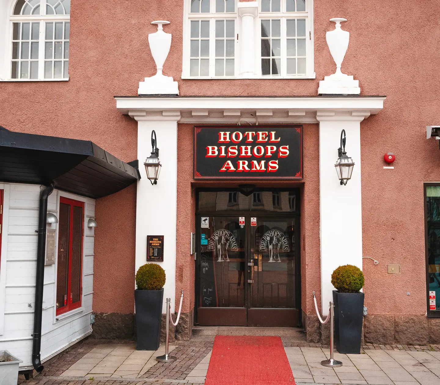 The entrance to the Bishops Arms Hotel with red carpet and plants outside