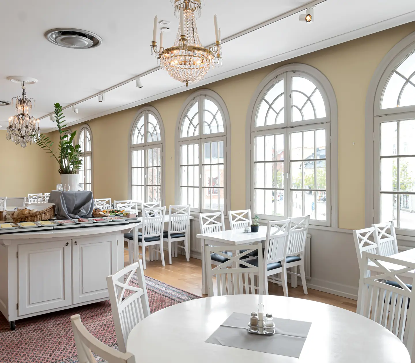 Bright breakfast room with white dining areas, buffet table and many large windows