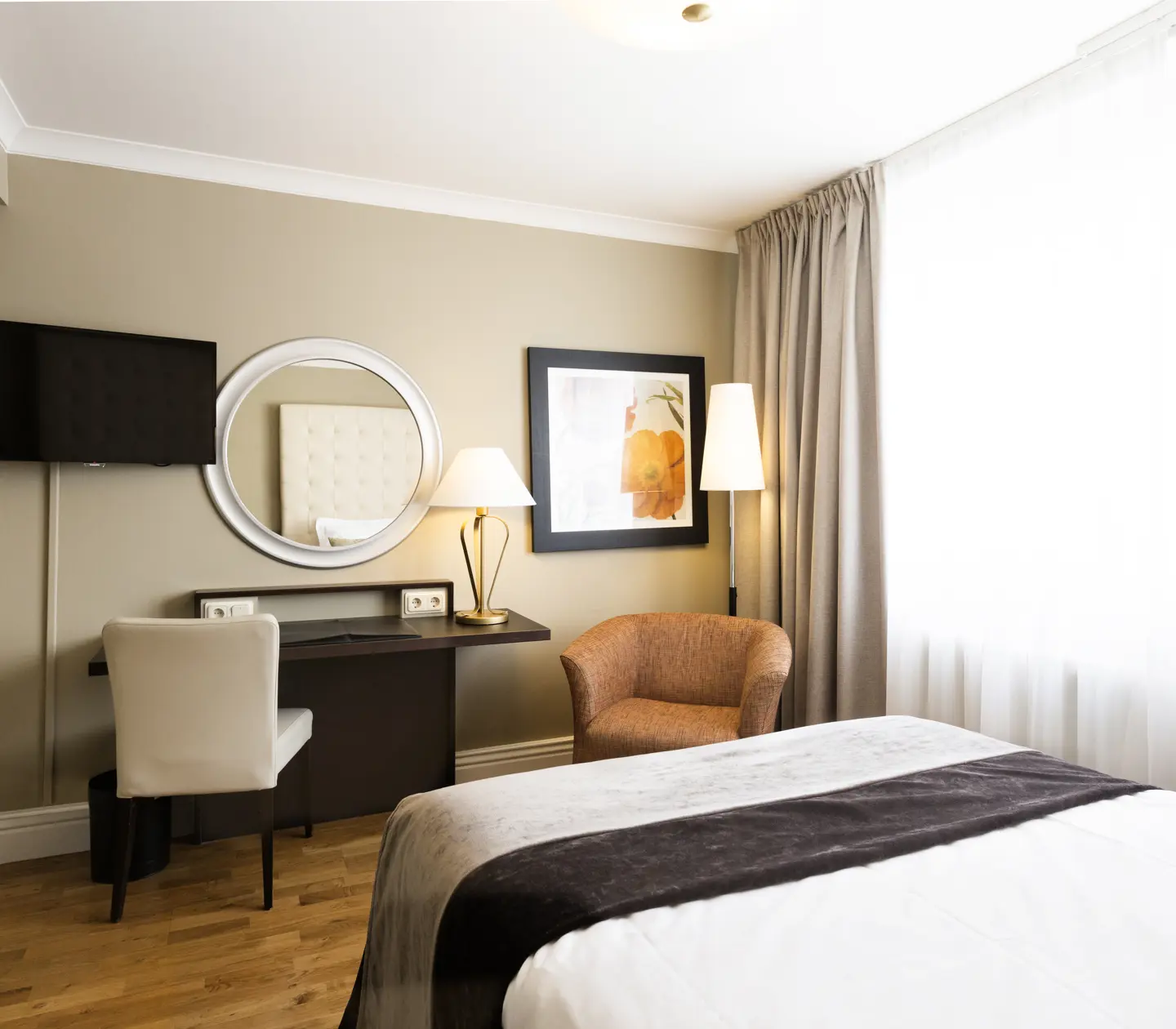 Small hotel room with bed, desk and armchair