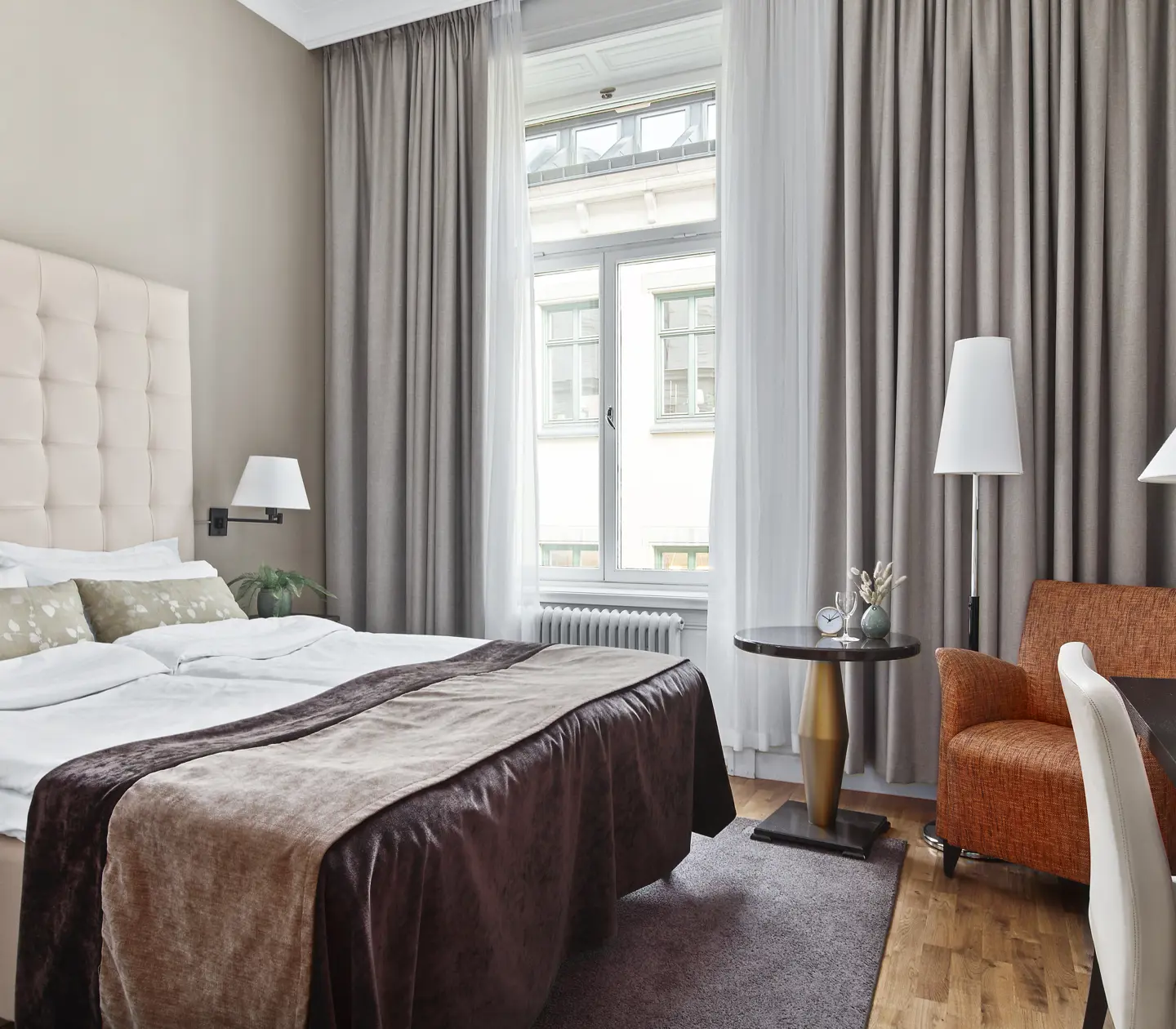 Bright hotel room with bed, white headboard and armchair