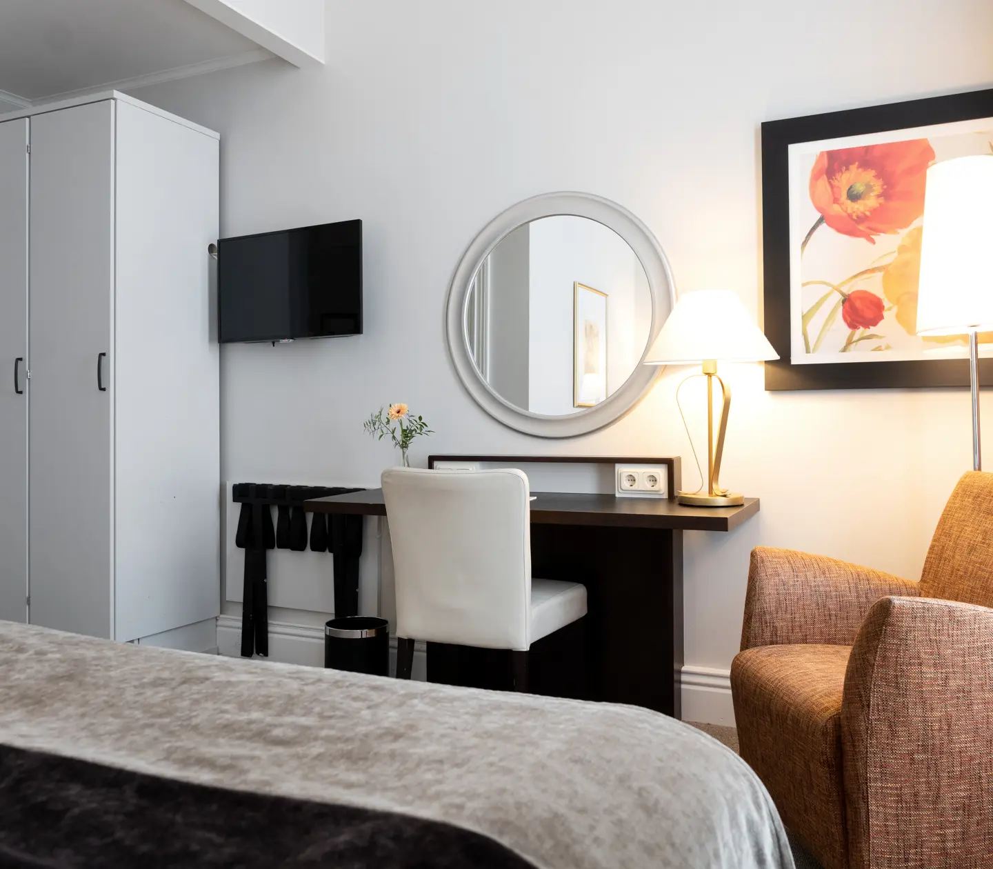 Bright hotel room with wardrobe, desk and armchair