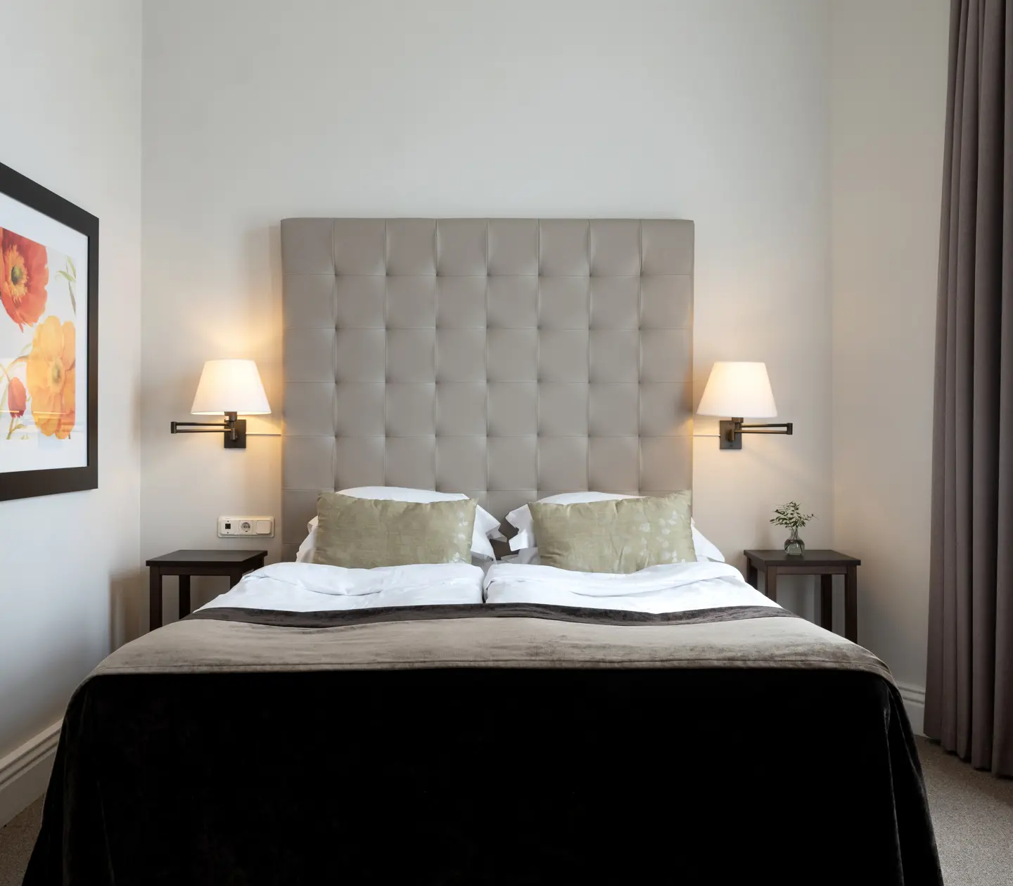 Bright hotel room with bed, gray headboard and painting