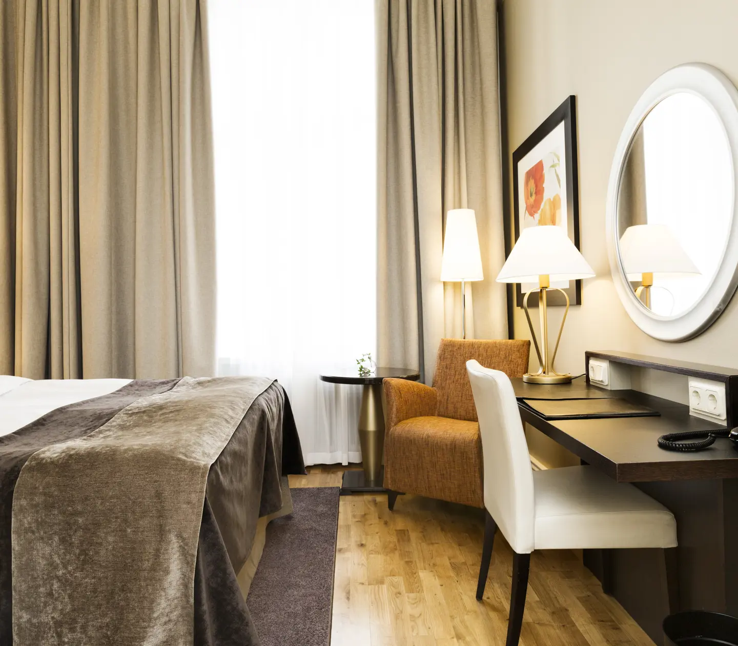 Bright hotel room with bed, desk and armchair