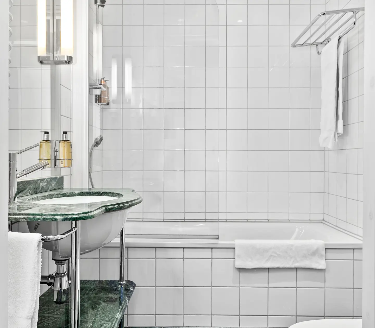 Bright bathroom with bathtub, green sink and towels