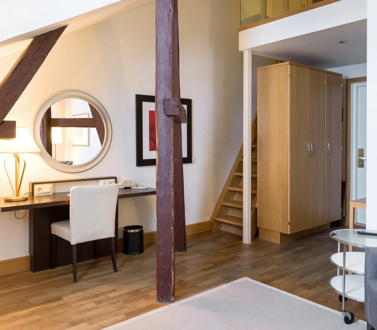Bright hotel room with wardrobe, desk and stairs to sleeping loft