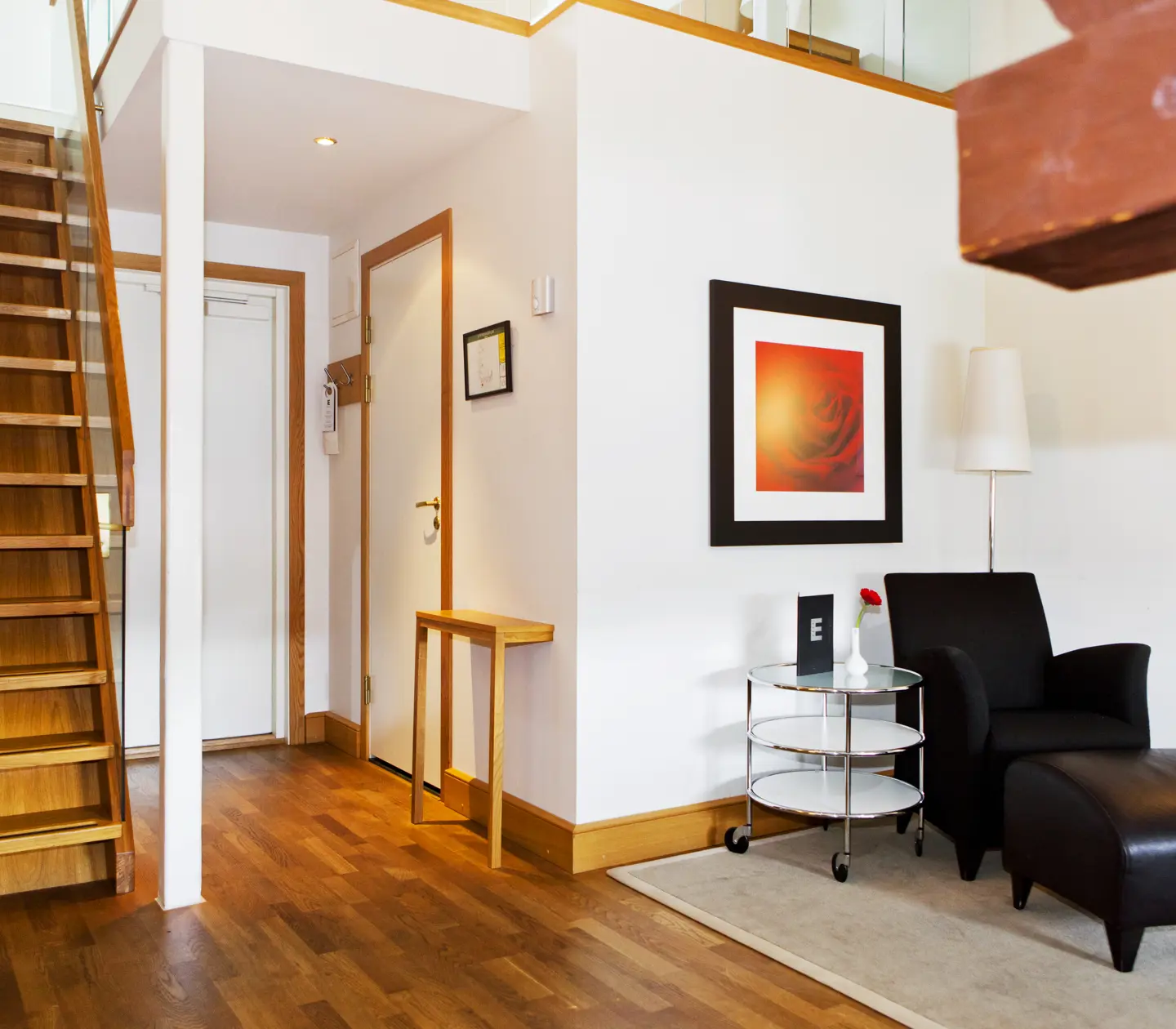 Bright hotel room with armchair, painting and stairs to sleeping loft