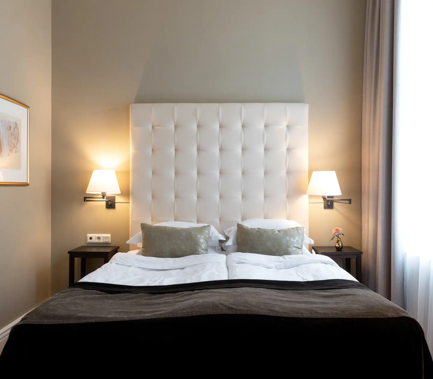 Bright hotel room with bed, white headboard and blackboard
