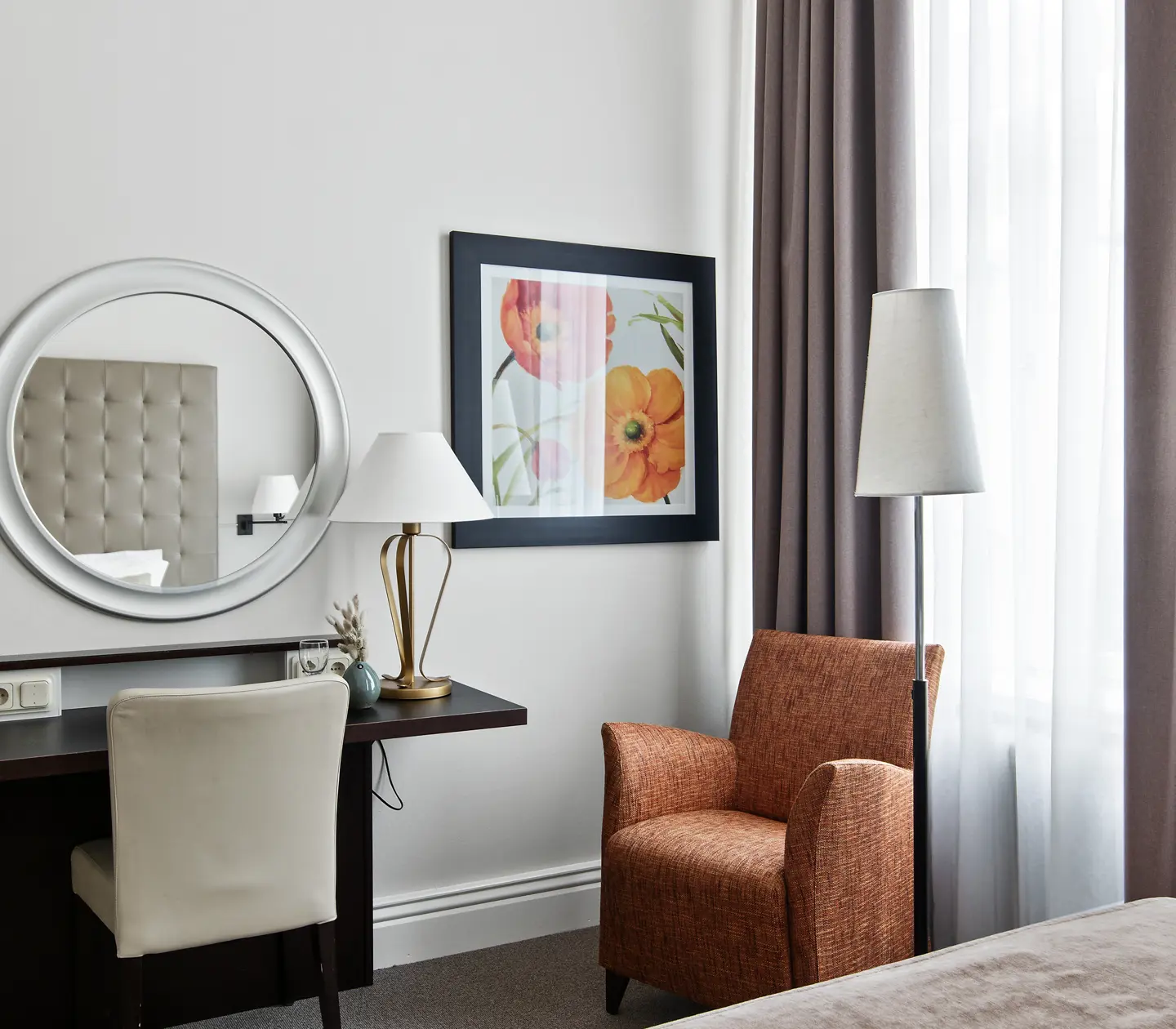 Bright hotel room with desk, armchair and round mirror