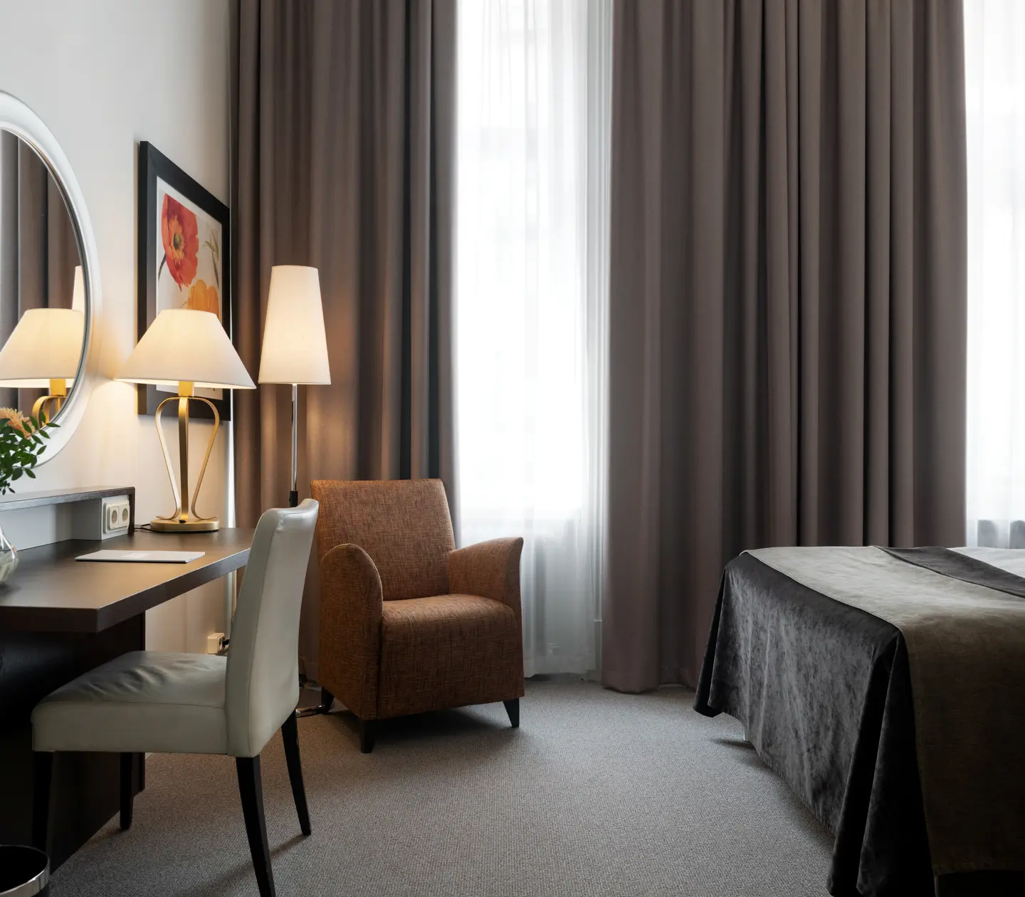 Bright hotel room with bed, desk and armchair
