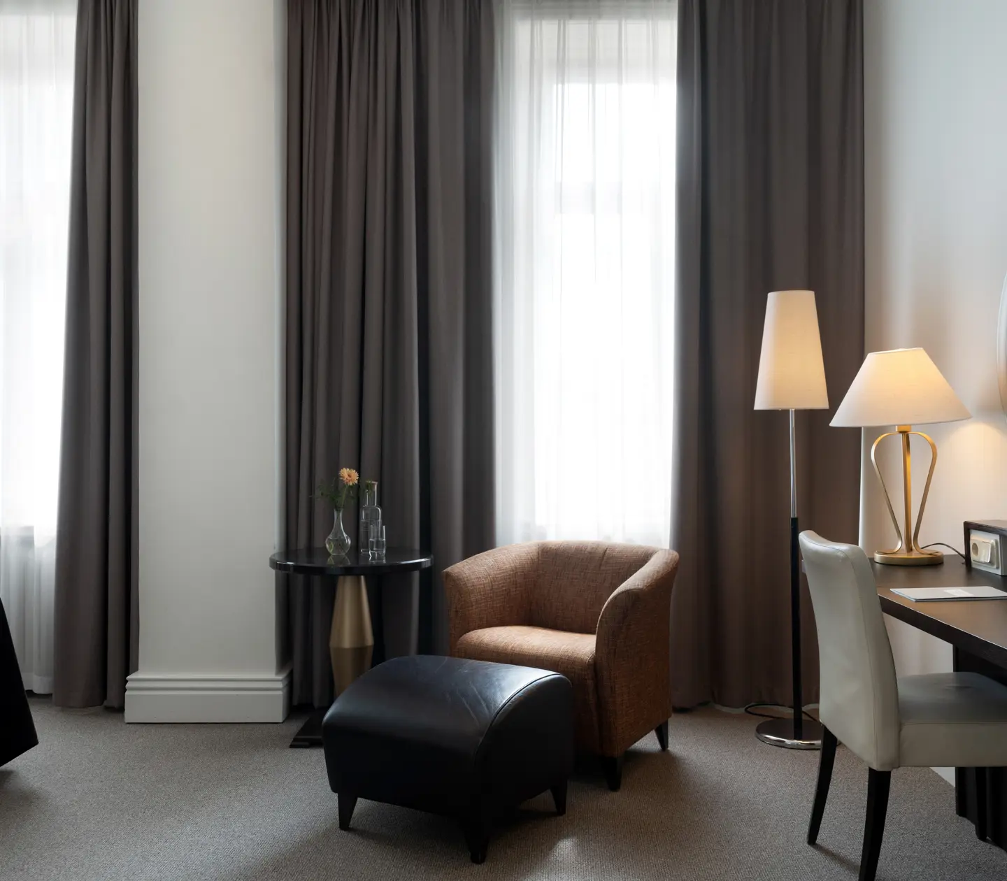 Bright hotel room with large windows, desk and armchair