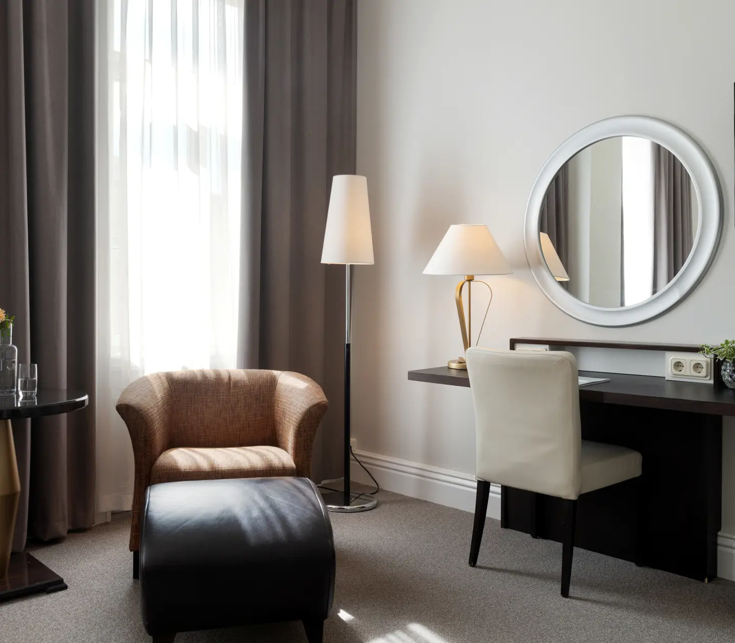 Bright hotel room with round mirror, desk and armchair