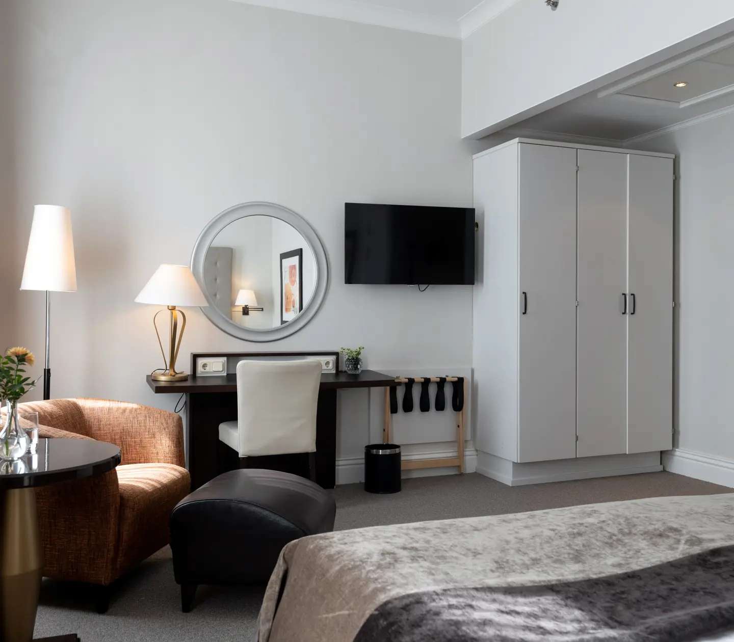 Bright hotel room with round mirror, wardrobe and armchair