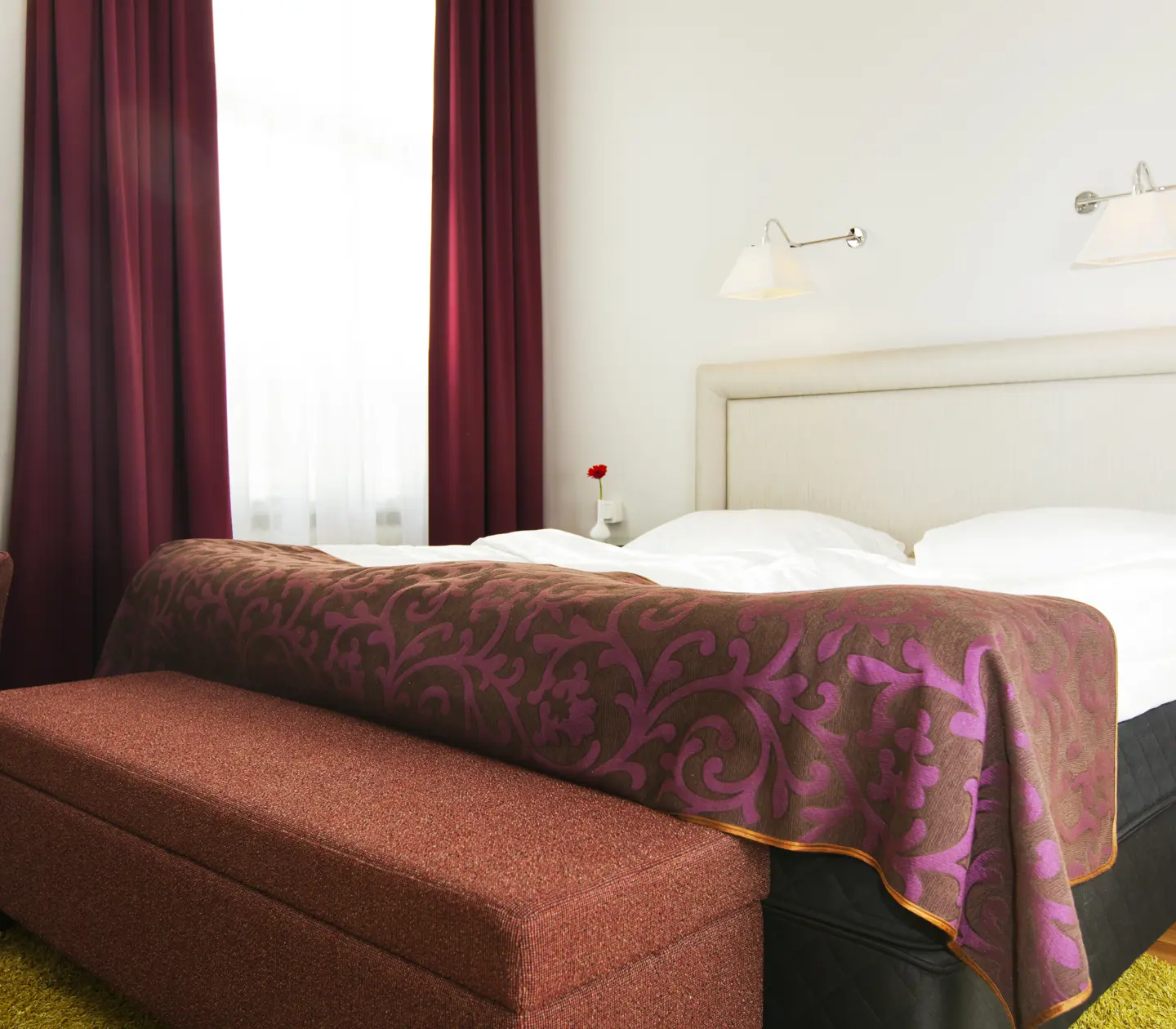 Bright hotel room with bed, white headboard and armchair