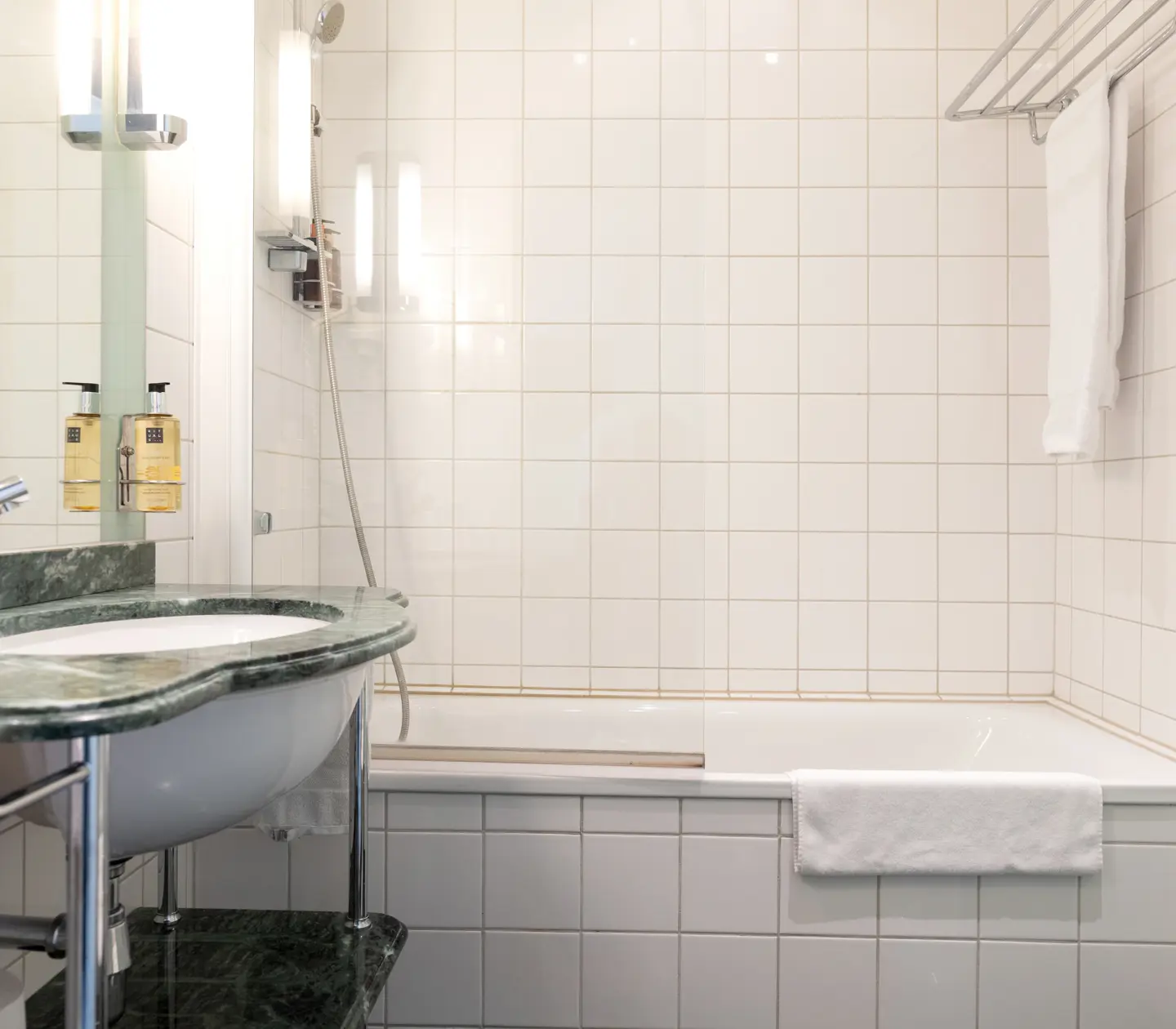 Bright bathroom with bathtub, green sink and towels