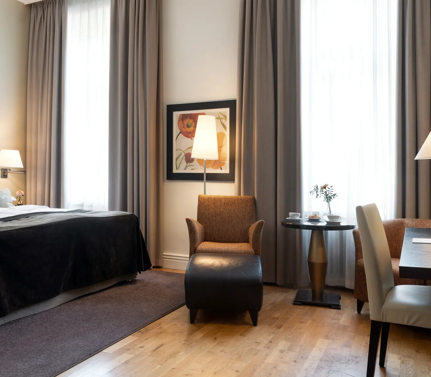 Bright hotel room with bed, desk and large windows