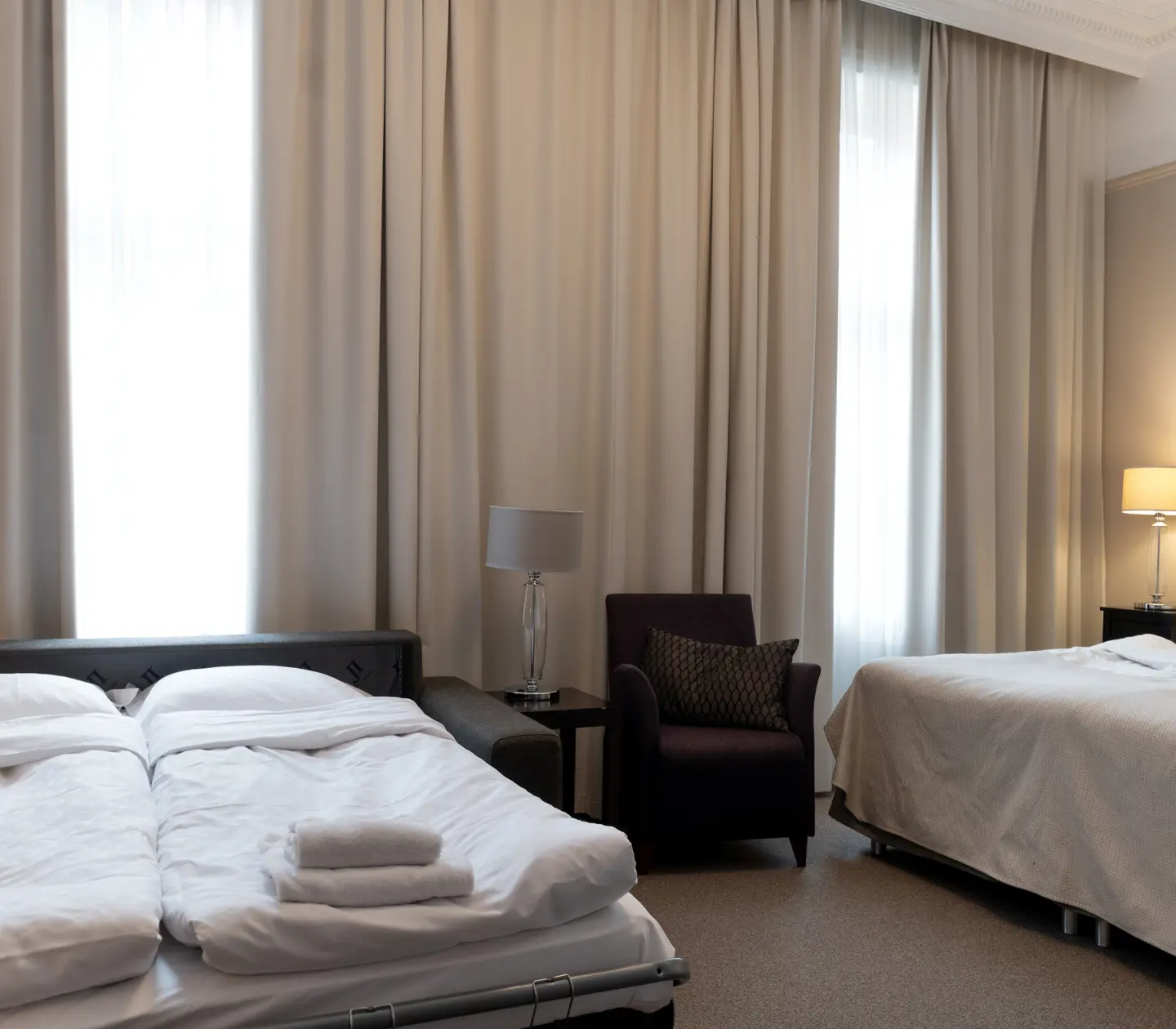 Bright hotel room with bed, armchair and sofa bed