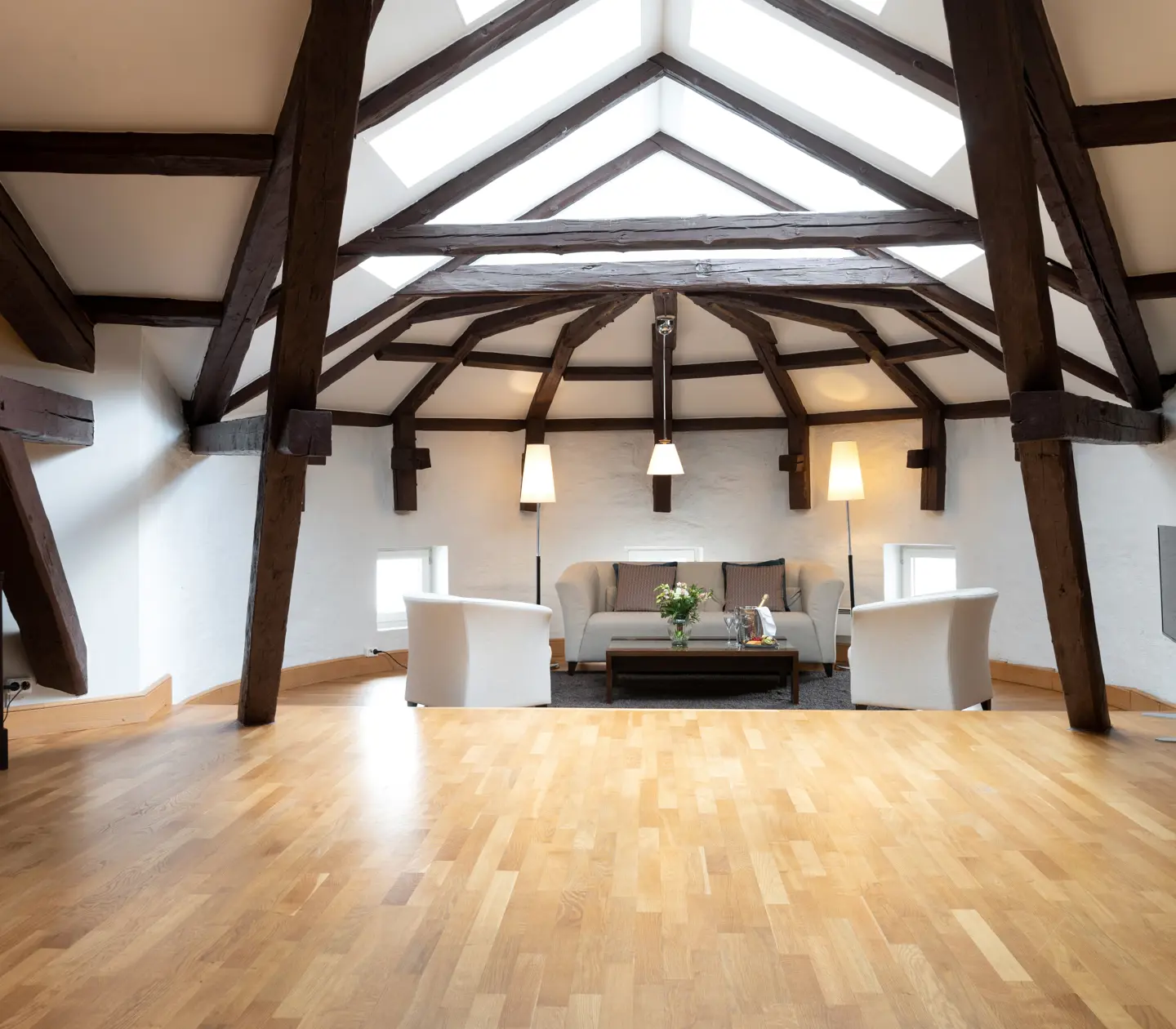 Bright suite with wooden beams from the ceiling, sofa group and skylight