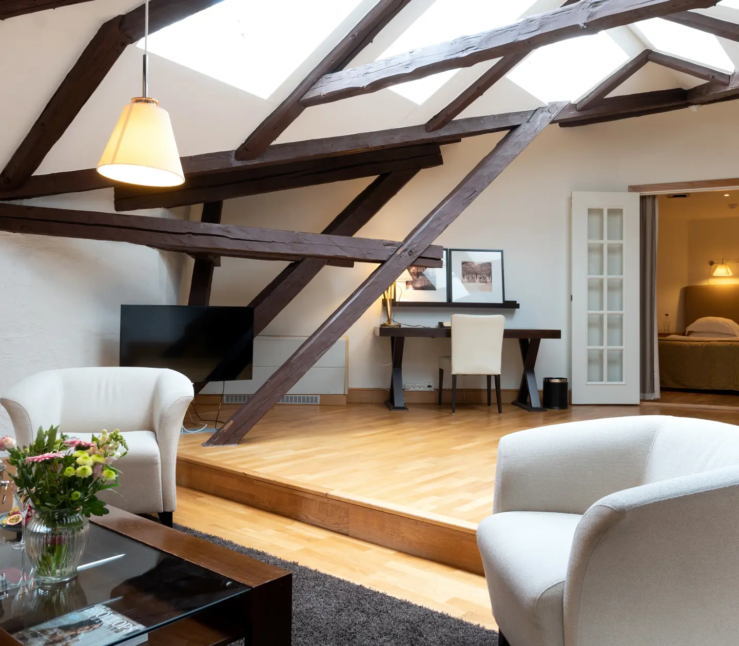 Bright suite with wooden beams from ceiling, armchairs and desk