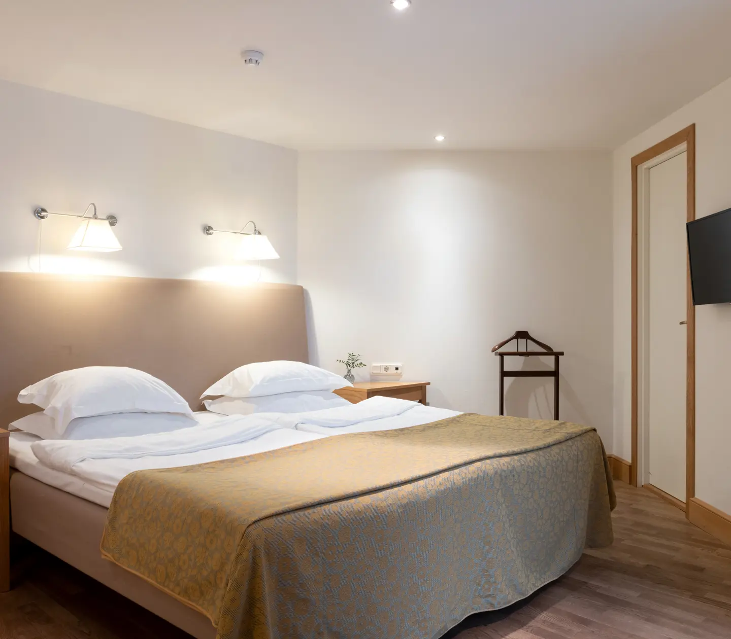 Bright suite with bed, bedside lamps and TV