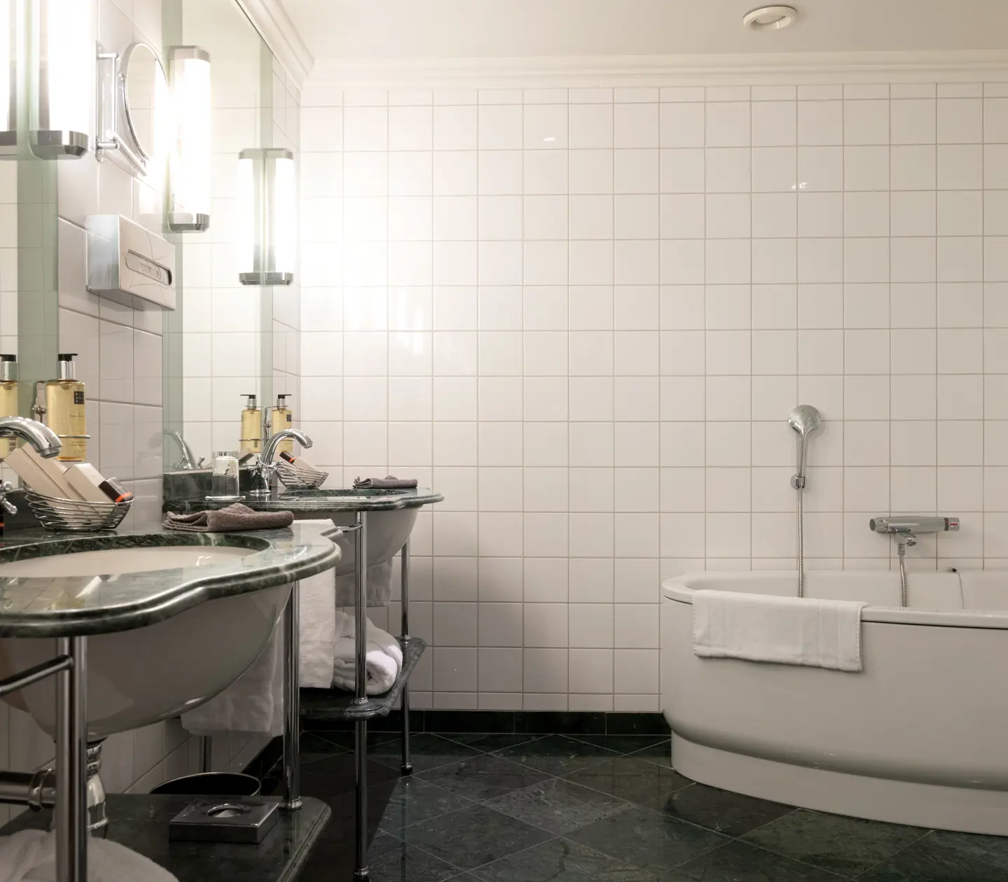 Bright bathroom with bathtub, double green sinks and towels