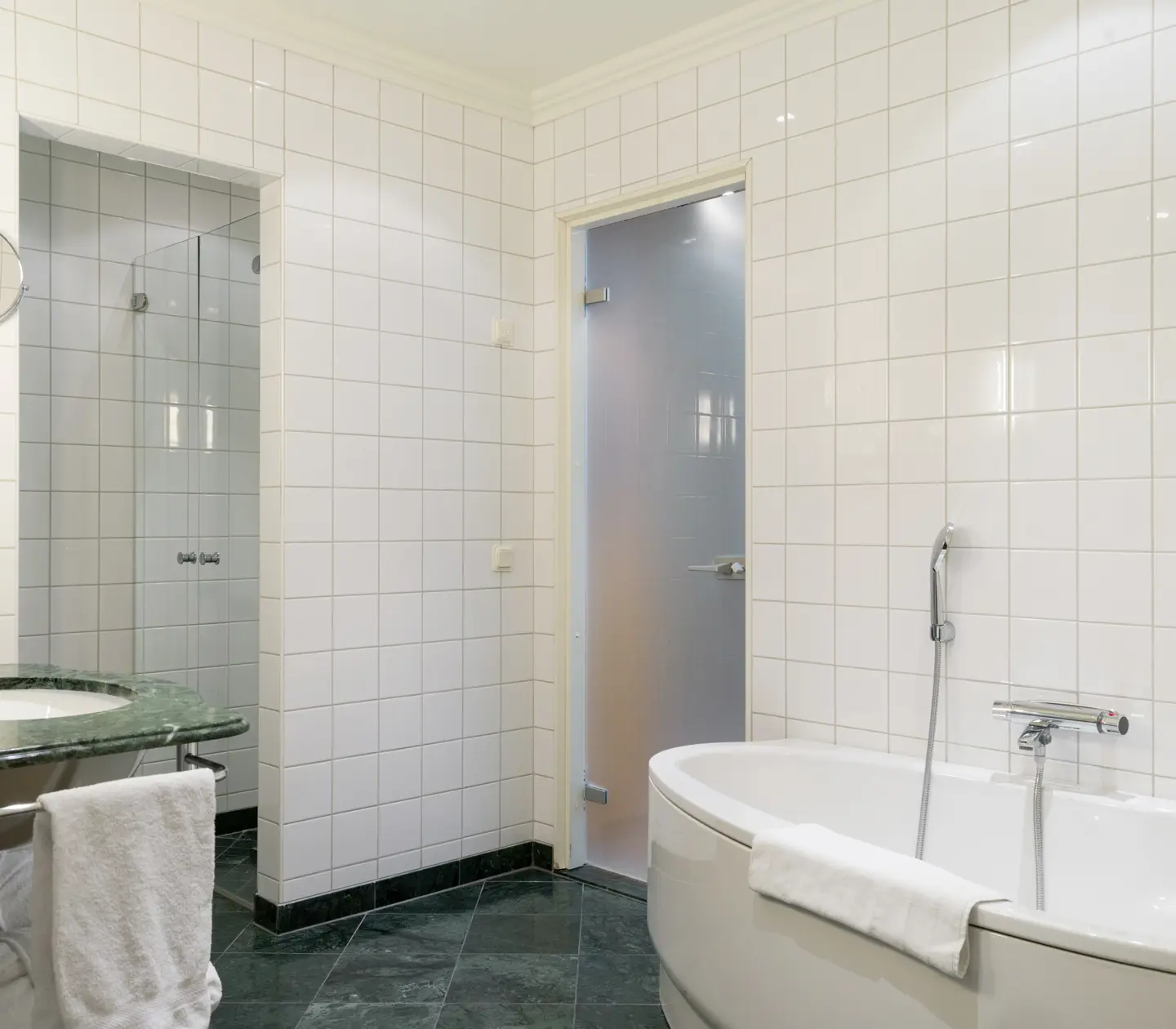Bright bathroom with bathtub, green sink and towels