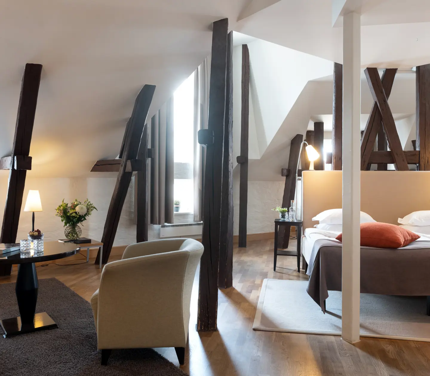 Bright suite with bed, sofa group and wooden beams from the ceiling